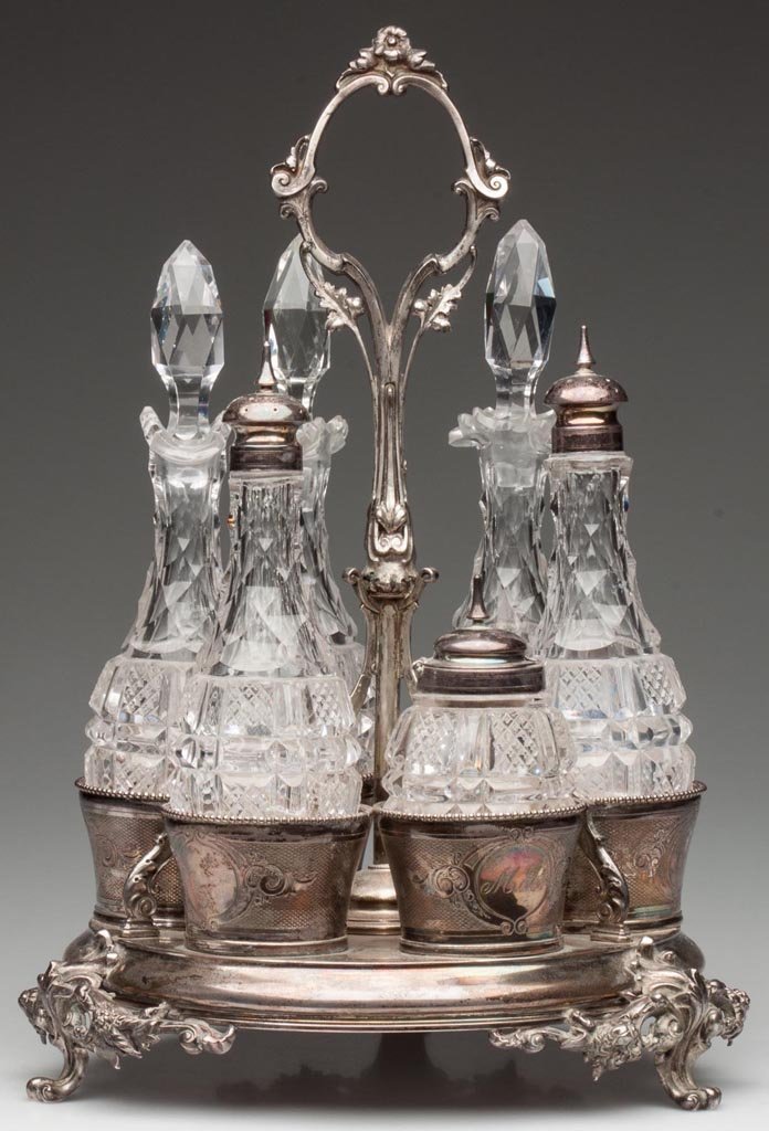 GORHAM COIN SILVER CRUET STAND: GORHAM COIN SILVER CRUET STAND, comprising a center handle surrounded by six beaded-rim cups with engine-turned decoration, raised on three scroll feet, one cup with "M.B" monogram. Cups fitted with m