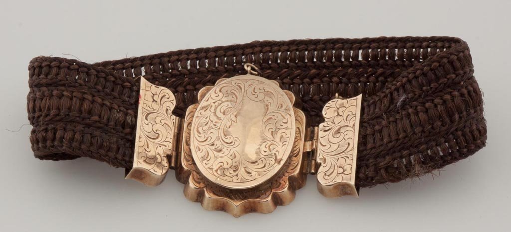 VICTORIAN GOLD AND HAIR BRACELET: VICTORIAN GOLD AND HAIR BRACELET, tested 10 karat gold, fittings are finely engraved, center hinged as a locket, with safety chain. Second half 19th century. 3/4" W, 7 5/8" L. Provenance: Property of 