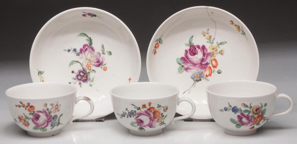 CONTINENTAL PORCELAIN TEAWARES, LOT OF FIVE: CONTINENTAL PORCELAIN TEAWARES, LOT OF FIVE, comprising three footed cups with simple handles with curled terminates, and two saucers, each painted in bright enamels with a large floral spray and a sm