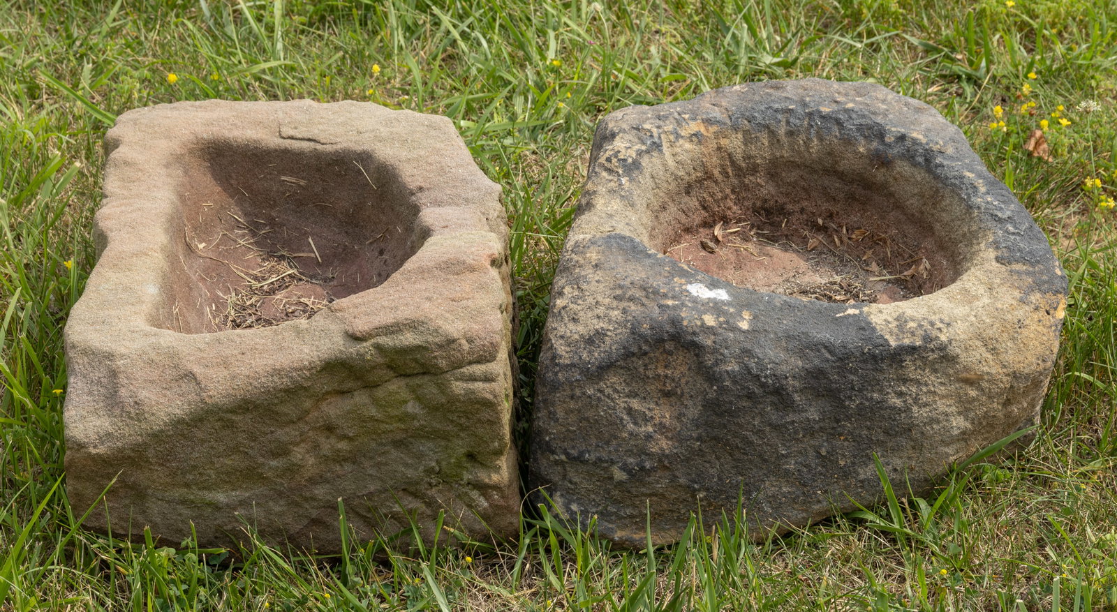 RUSTIC CARVED-STONE DIMINUTIVE TROUGHS, LOT OF TWO: RUSTIC CARVED-STONE DIMINUTIVE TROUGHS, LOT OF TWO, each of naturalistic form, one with a D-shaped well in the center, the other with a round well. 19th/20th century. Largest 19" x 13" OA.