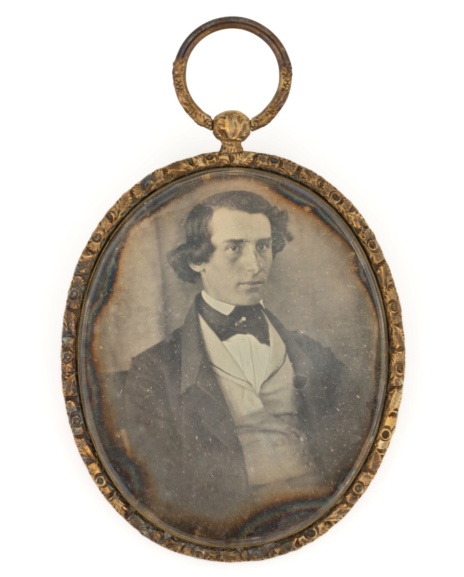 AMERICAN OR BRITISH NINTH-PLATE DAGUERREOTYPE PORTRAIT IN GOLD FRAME: AMERICAN OR BRITISH NINTH-PLATE DAGUERREOTYPE PORTRAIT IN GOLD FRAME, depicting a young man with brown hair dressed in a fine suit with an ornate pin securing his cravat. Housed in an oval frame that 