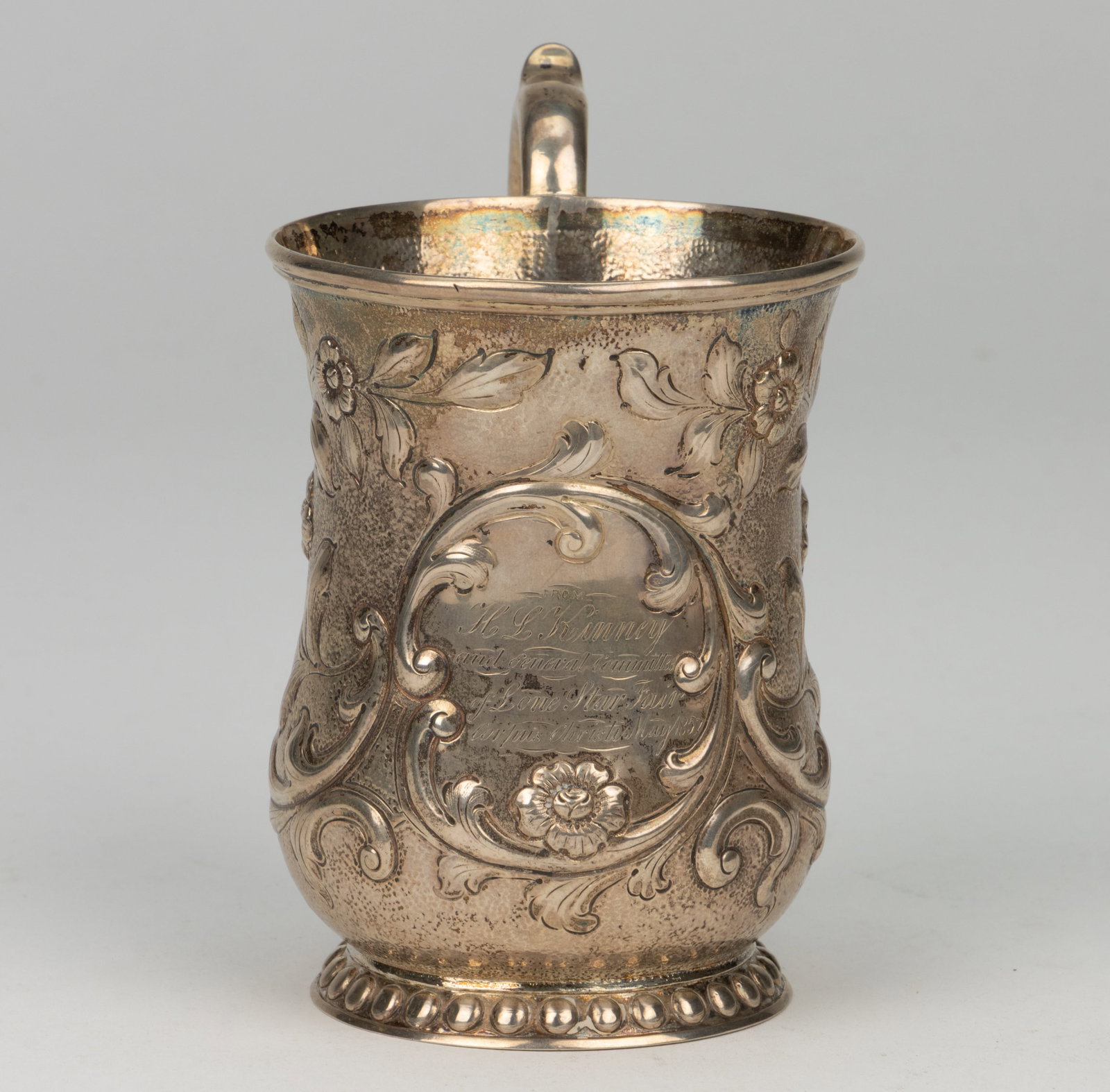 LONE STAR FAIR OF 1852, CORPUS CHRISTI, TEXAS PRESENTATION COIN SILVER MUG: LONE STAR FAIR OF 1852, CORPUS CHRISTI, TEXAS PRESENTATION COIN SILVER MUG, baluster-form well having all-over repousse, chased, and engraved decoration of flowers and scrolling leaves, one side with 