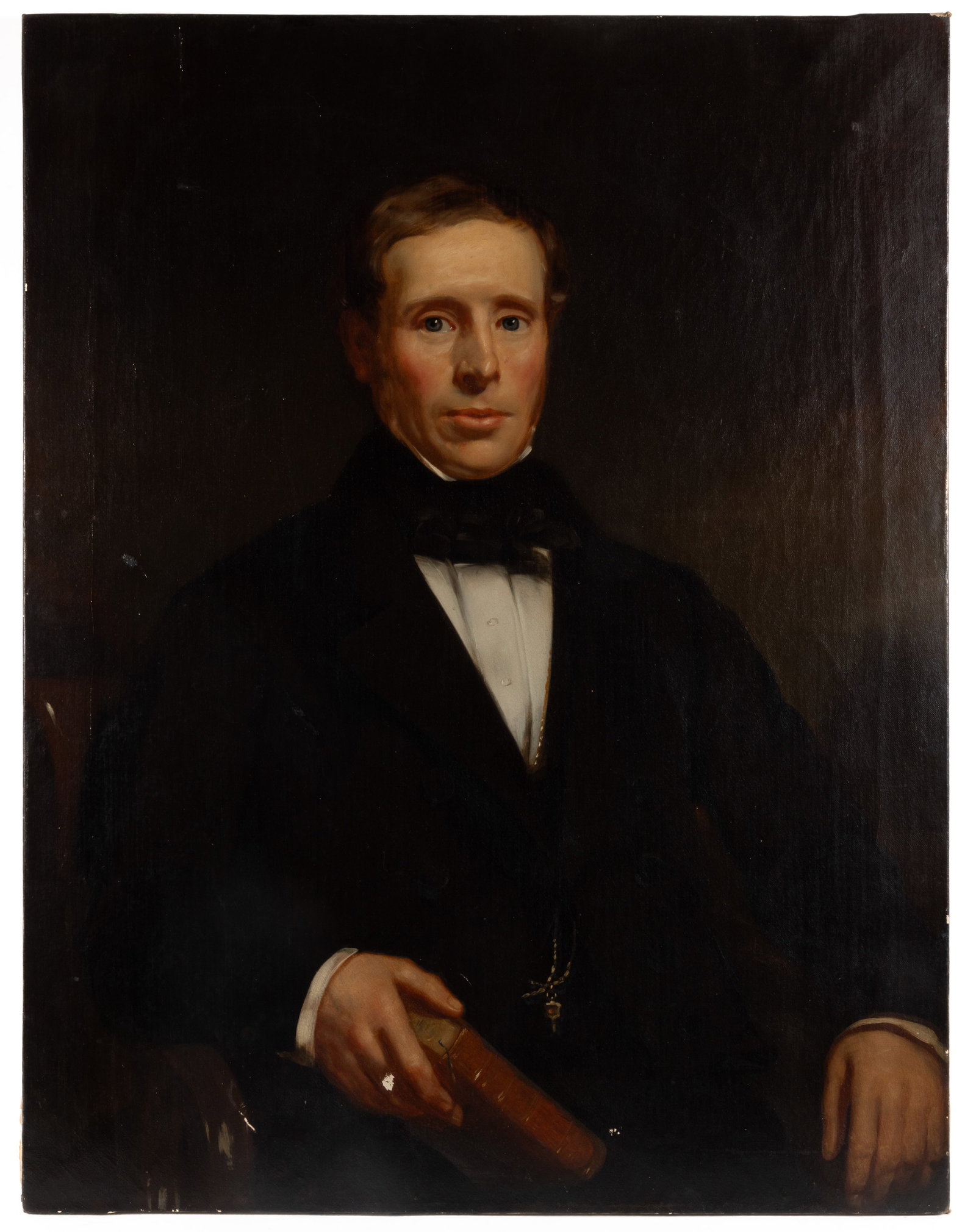 AMERICAN SCHOOL (19TH CENTURY) PORTRAIT OF A GENTLEMAN: AMERICAN SCHOOL (19TH CENTURY) PORTRAIT OF A GENTLEMAN, oil on canvas, a waist-length depiction of a sandy-haired gentleman with bright blue eyes, in his hands he holds a book, and around his neck he 