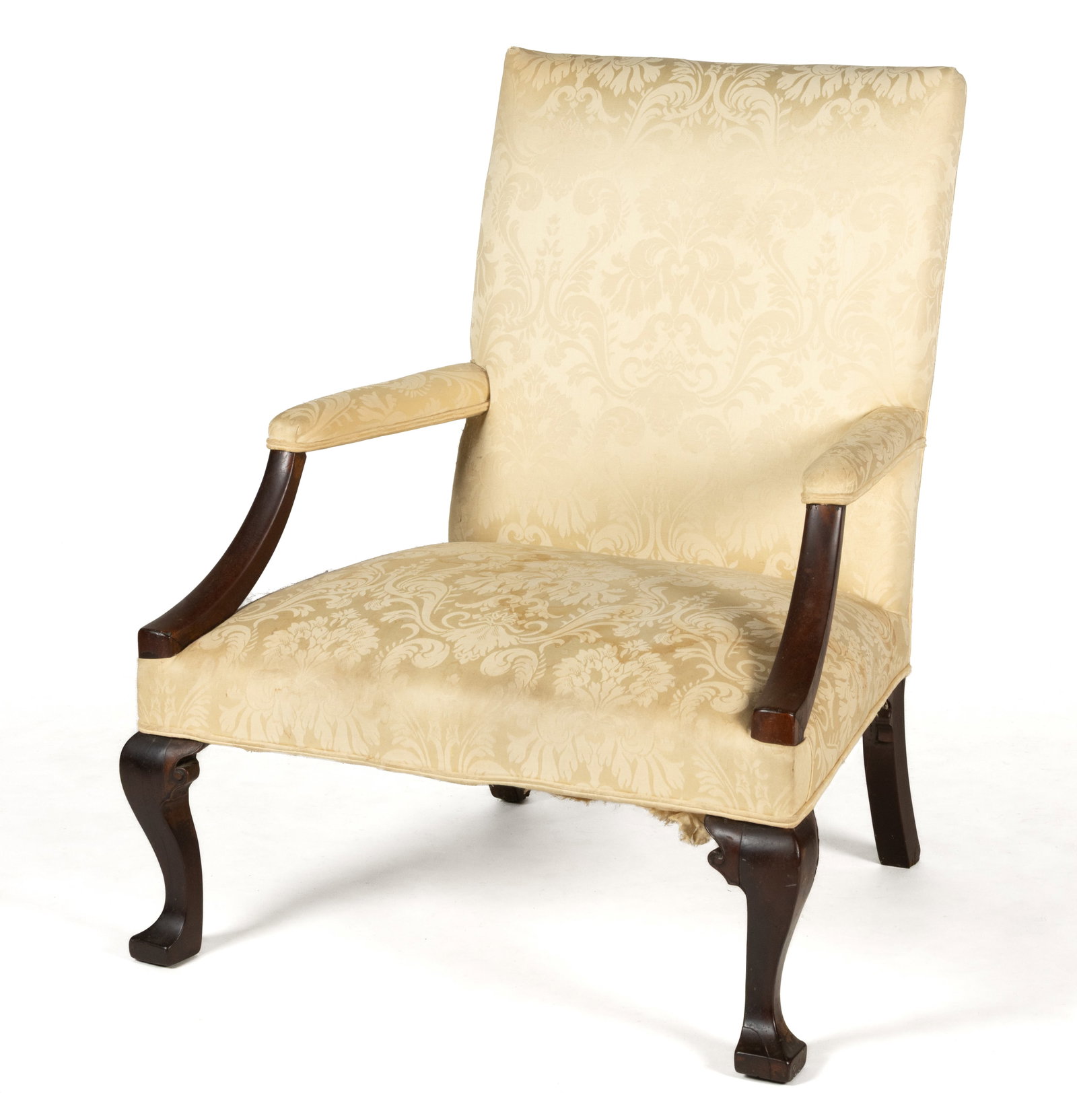 AMERICAN OR ENGLISH MAHOGANY LOLLING CHAIR: AMERICAN OR ENGLISH MAHOGANY LOLLING CHAIR, generous form in the Queen Anne style with open arms and cabriole legs ending in stylized feet, upholstered in creamy yellow silk damask. Fourth