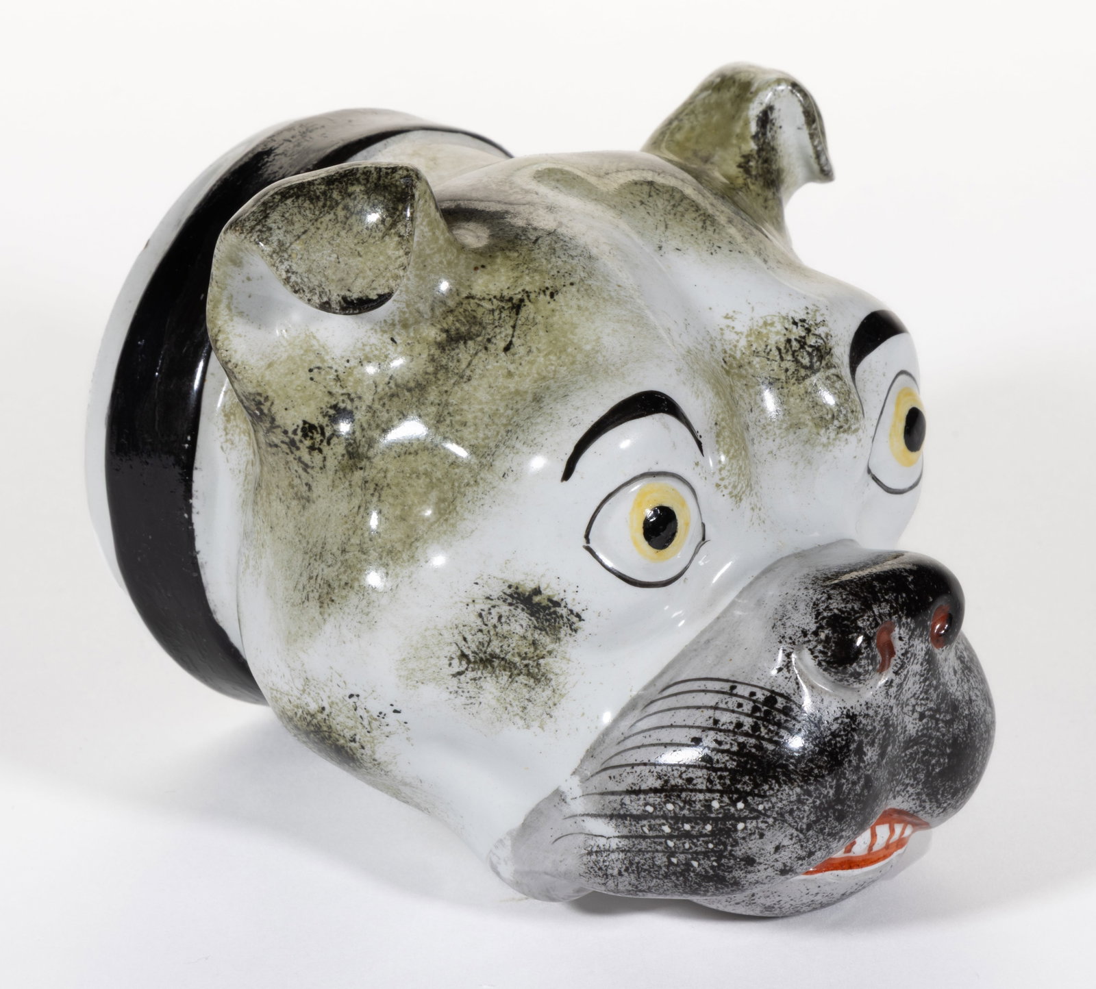 ENGLISH HAND-PAINTED CERAMIC DOG STIRRUP CUP: ENGLISH HAND-PAINTED CERAMIC DOG STIRRUP CUP, having polychrome enamel decorations, depicting a wide-eyed bulldog with folded ears and wearing a buckled collar. Third quarter 19th century. 4 3/8"
