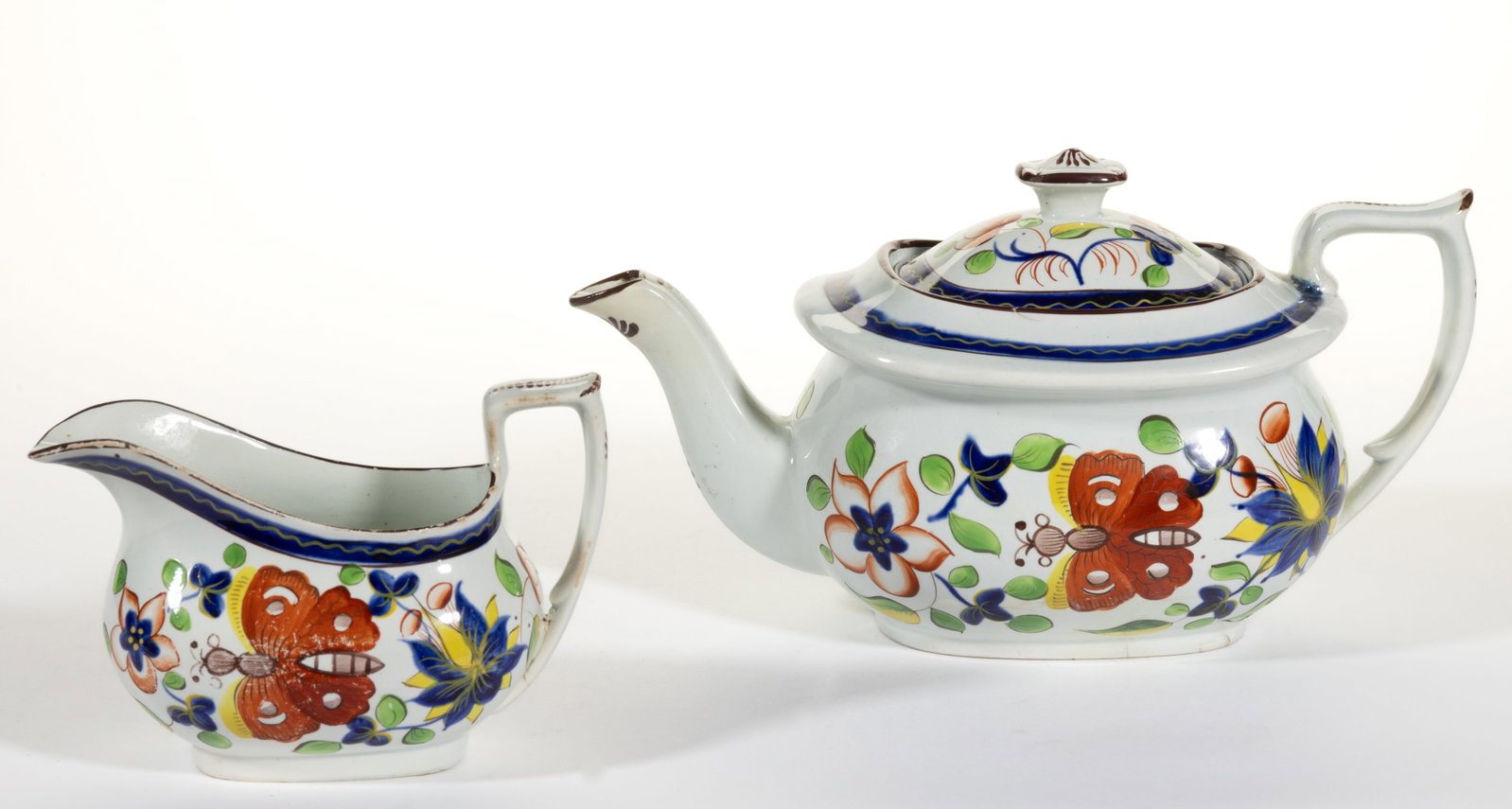 ENGLISH PEARLWARE GAUDY DUTCH BUTTERFLY MOTIF CERAMIC TEA ARTICLES, LOT OF TWO: ENGLISH PEARLWARE GAUDY DUTCH BUTTERFLY MOTIF CERAMIC TEA ARTICLES, LOT OF TWO, each featuring bold polychrome Butterfly design, comprising a teapot and a creamer. Each having hand-brushed "x&quo