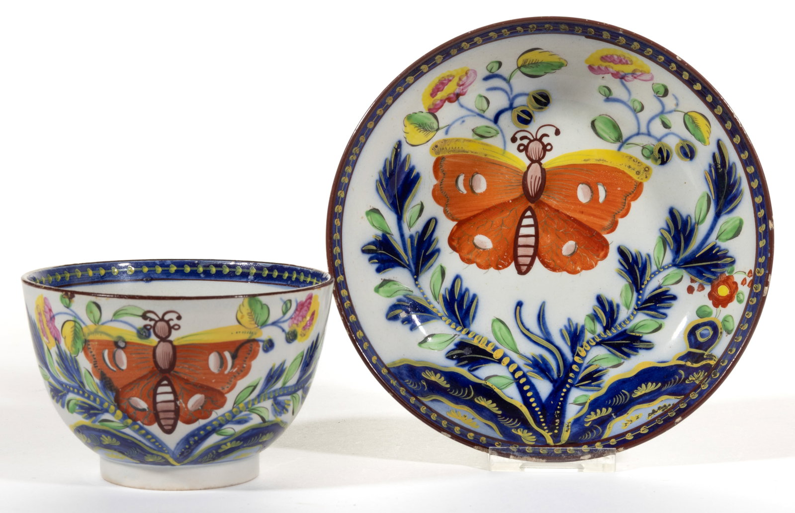 ENGLISH PEARLWARE GAUDY DUTCH BUTTERFLY MOTIF CERAMIC CUP AND SAUCER SET: ENGLISH PEARLWARE GAUDY DUTCH BUTTERFLY MOTIF CERAMIC CUP AND SAUCER SET, featuring bold polychrome central butterfly design. Unmarked. First quarter 19th century. 2 3/8" HOA, 5 3/8" D sauce
