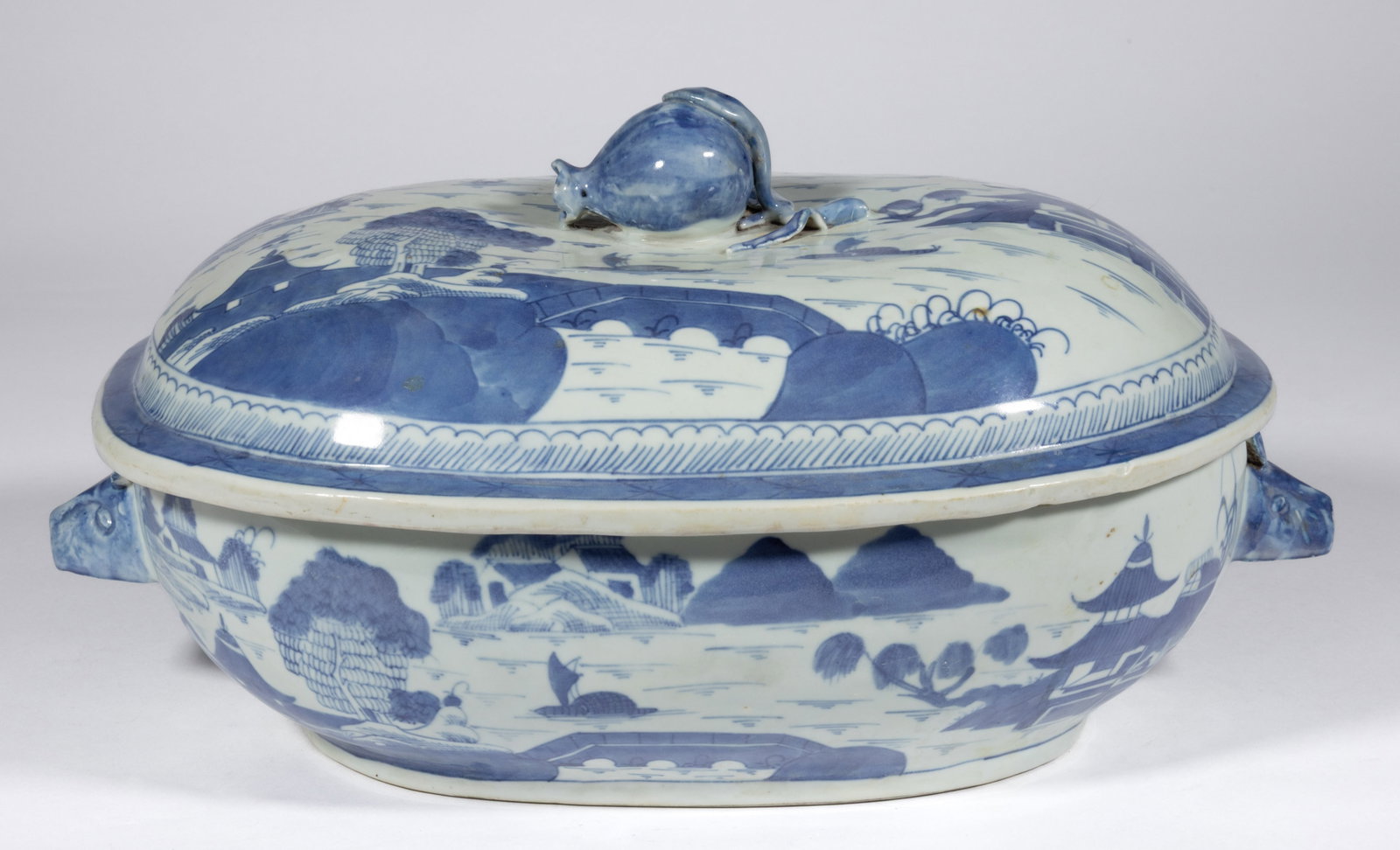 CHINESE EXPORT PORCELAIN BLUE AND WHITE CANTON SOUP TUREEN WITH COVER: CHINESE EXPORT PORCELAIN BLUE AND WHITE CANTON SOUP TUREEN WITH COVER, ovoid form with molded boar's head handles and cover with figural pomegranate finial, featuring a hand-painted land