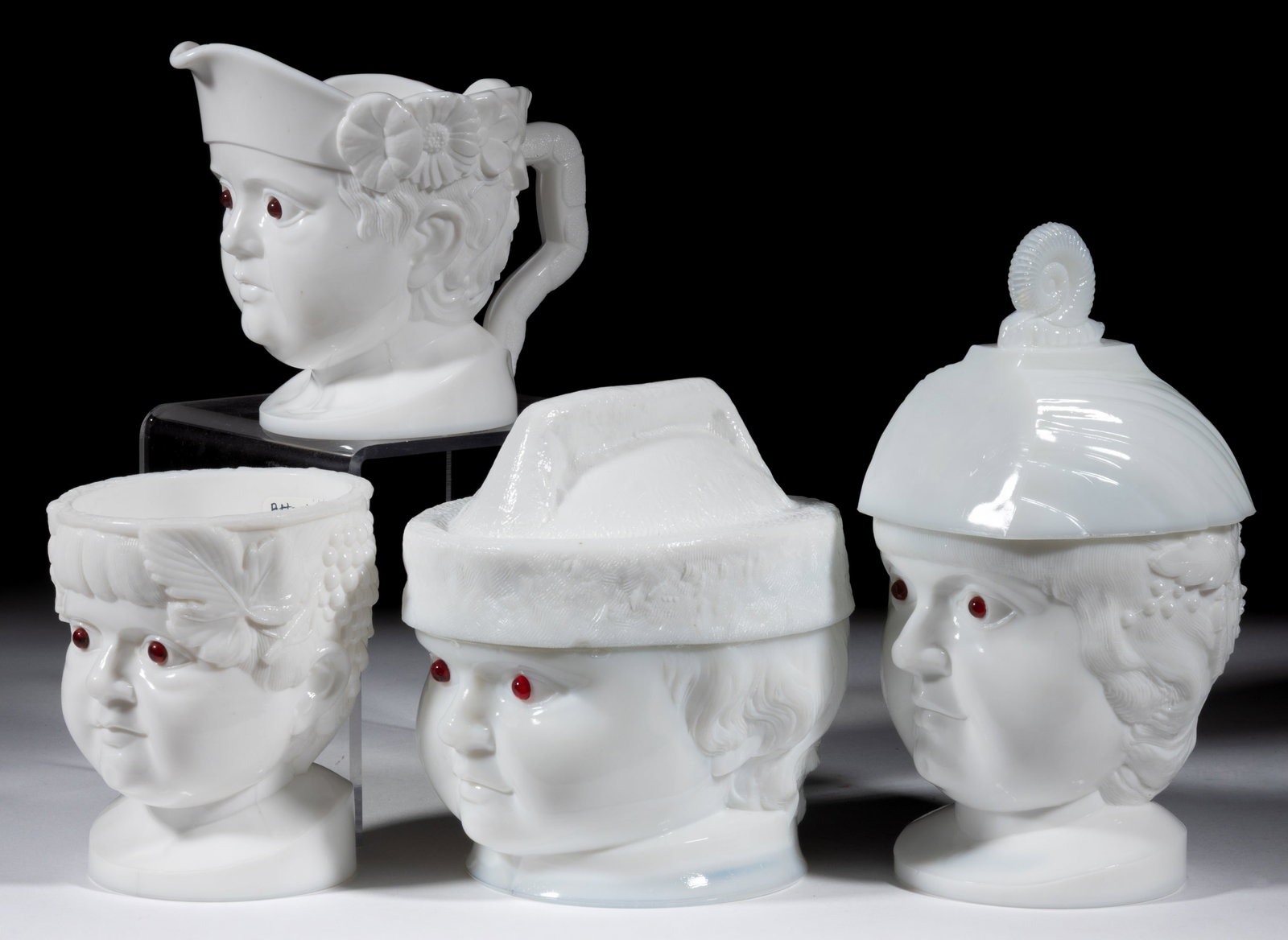 THE FAMILY FOUR-PIECE TABLE SET: THE FAMILY FOUR-PIECE TABLE SET, opaque white/milk glass, applied red eyes, comprising a covered butter dish, covered sugar bowl, creamer, and spooner. Fourth quarter 19th century. 4 5/8" to