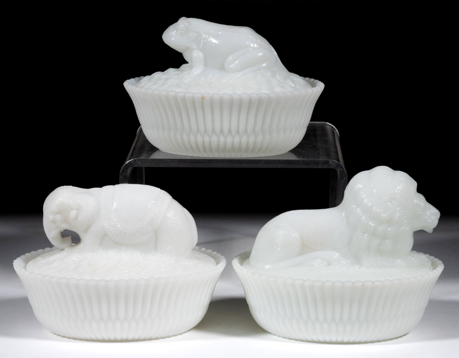 ASSORTED MCKEE NOVELTY FIGURAL ANIMAL COVERED DISHES, LOT OF THREE: ASSORTED MCKEE NOVELTY FIGURAL ANIMAL COVERED DISHES, LOT OF THREE, opaque white/milk glass, comprising an elephant, frog, and lion, each with split-rib base, each marked "McKEE" to the