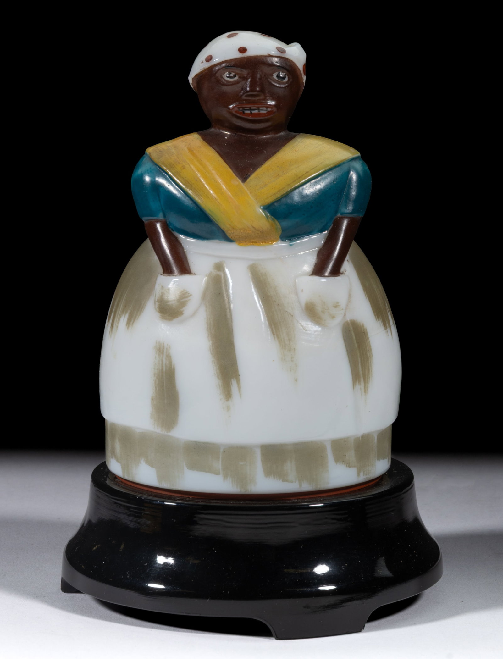 BLACK AMERICANA MAMMY FIGURAL ELECTRIC LAMP: BLACK AMERICANA MAMMY FIGURAL ELECTRIC LAMP, opaque white/milk glass with realistic paint decoration to the face and clothing, hollow figure on original opaque black glass base raised on four obl
