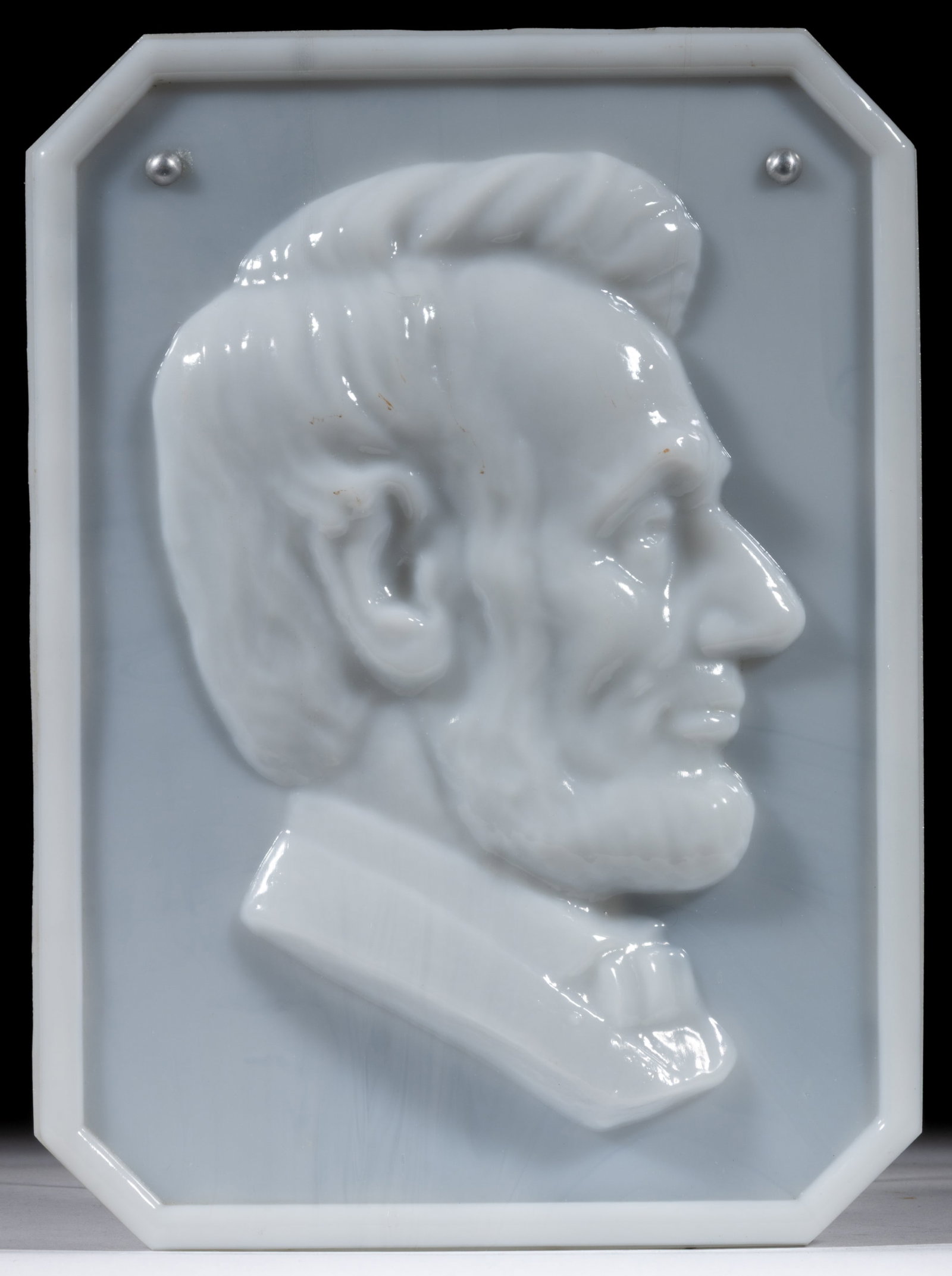 ABRAHAM LINCOLN PLAQUE: ABRAHAM LINCOLN PLAQUE, opaque white/milk glass with black paint application to the underside, high relief profile, retains metal pins and cord to underside. Maker unverified. Circa 1864. 10 3/4"