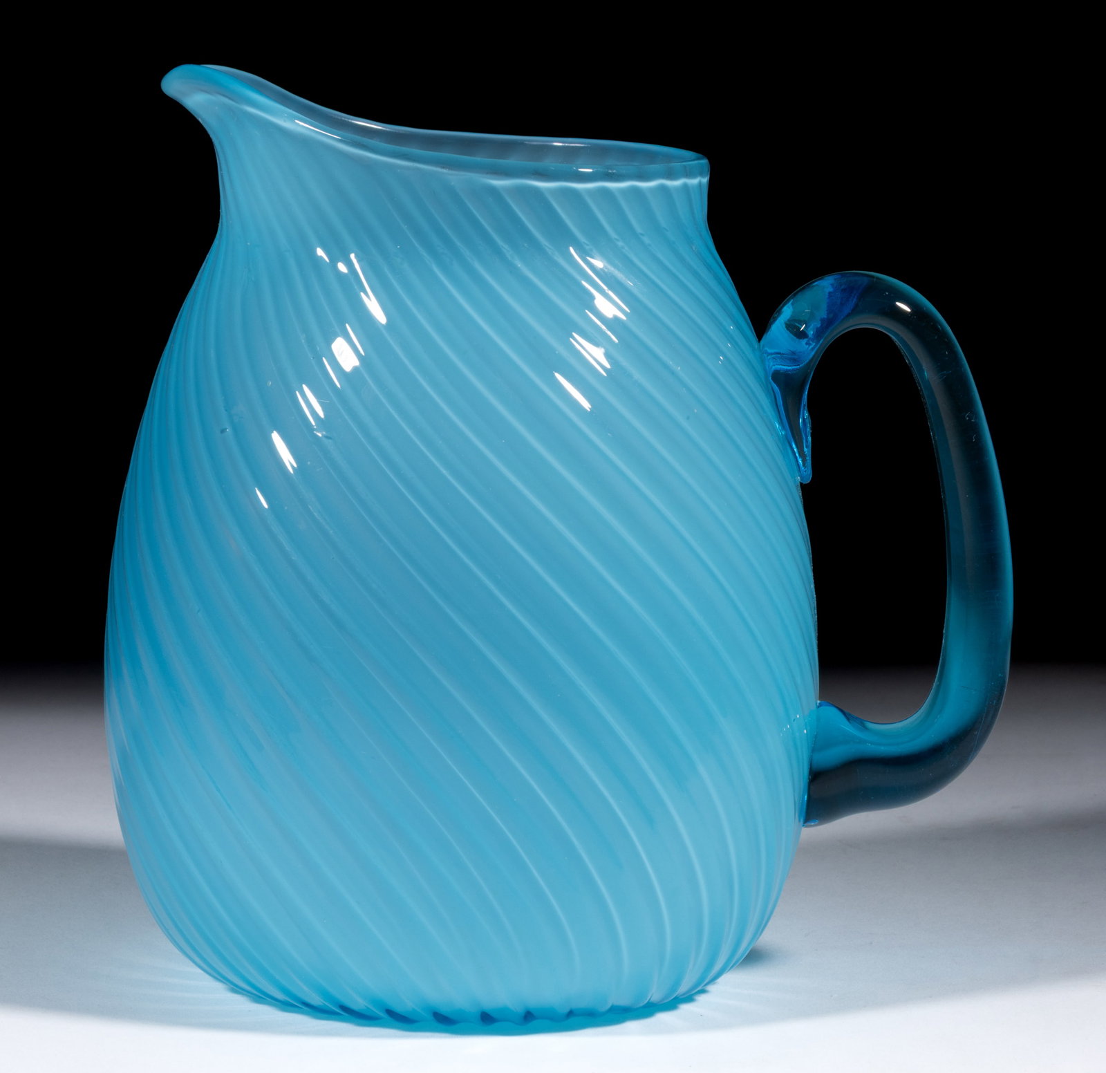 HOBBS NO. 207 / MURANO WATER PITCHER: HOBBS NO. 207 / MURANO WATER PITCHER, sapphire alabaster/blue cased, swirled optic ribs, ovoid rim, applied transparent blue handle, polished pontil mark. Hobbs, Brockunier & Co. Circa 1887. 7 1/2