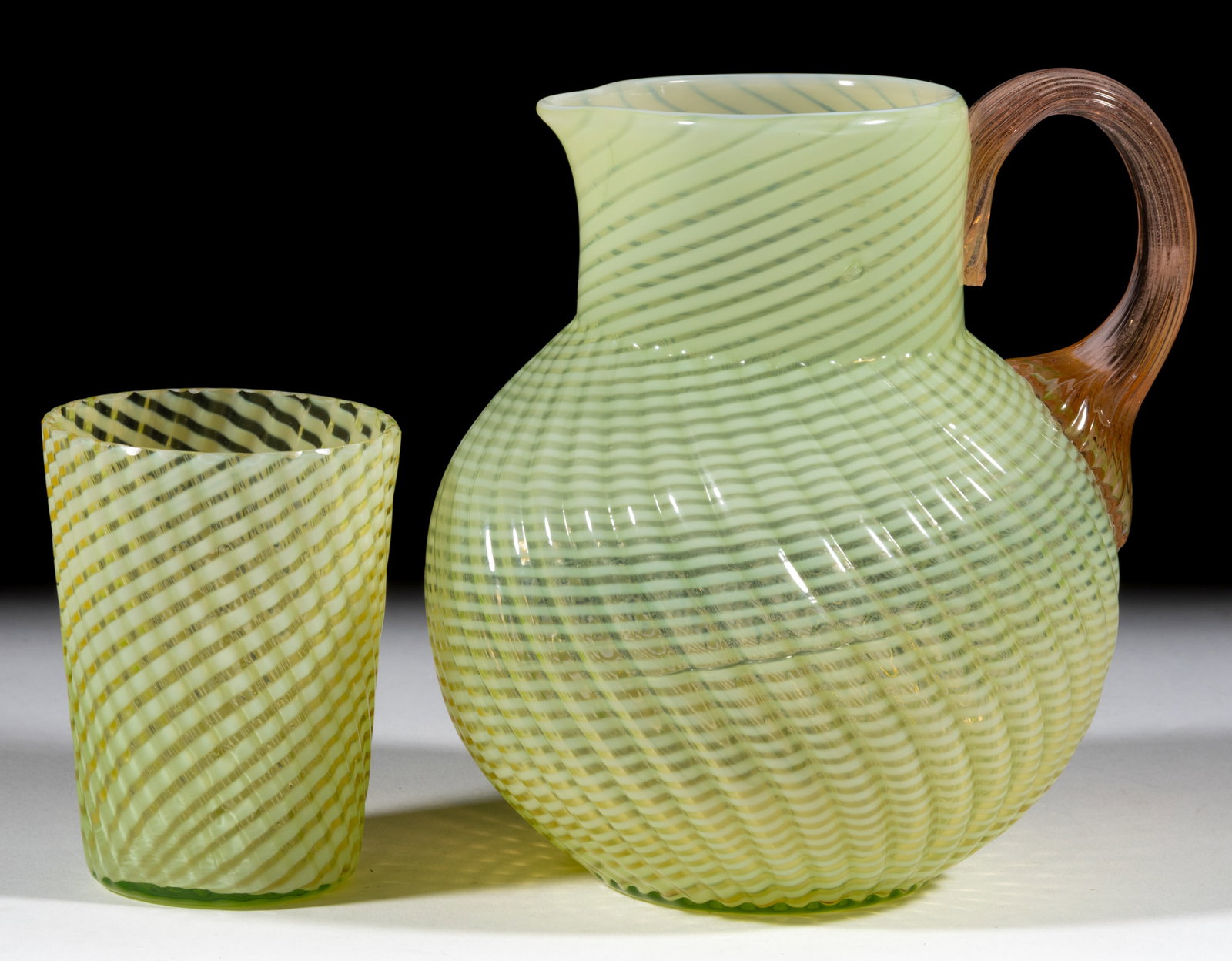 REVERSE OPALESCENT SWIRL PITCHER AND TUMBLER, LOT OF TWO: REVERSE OPALESCENT SWIRL PITCHER AND TUMBLER, LOT OF TWO, Vaseline opalescent (reacts under black light), a ball-form pitcher with circular rim with applied rose color reeded handle and a tapered tumb