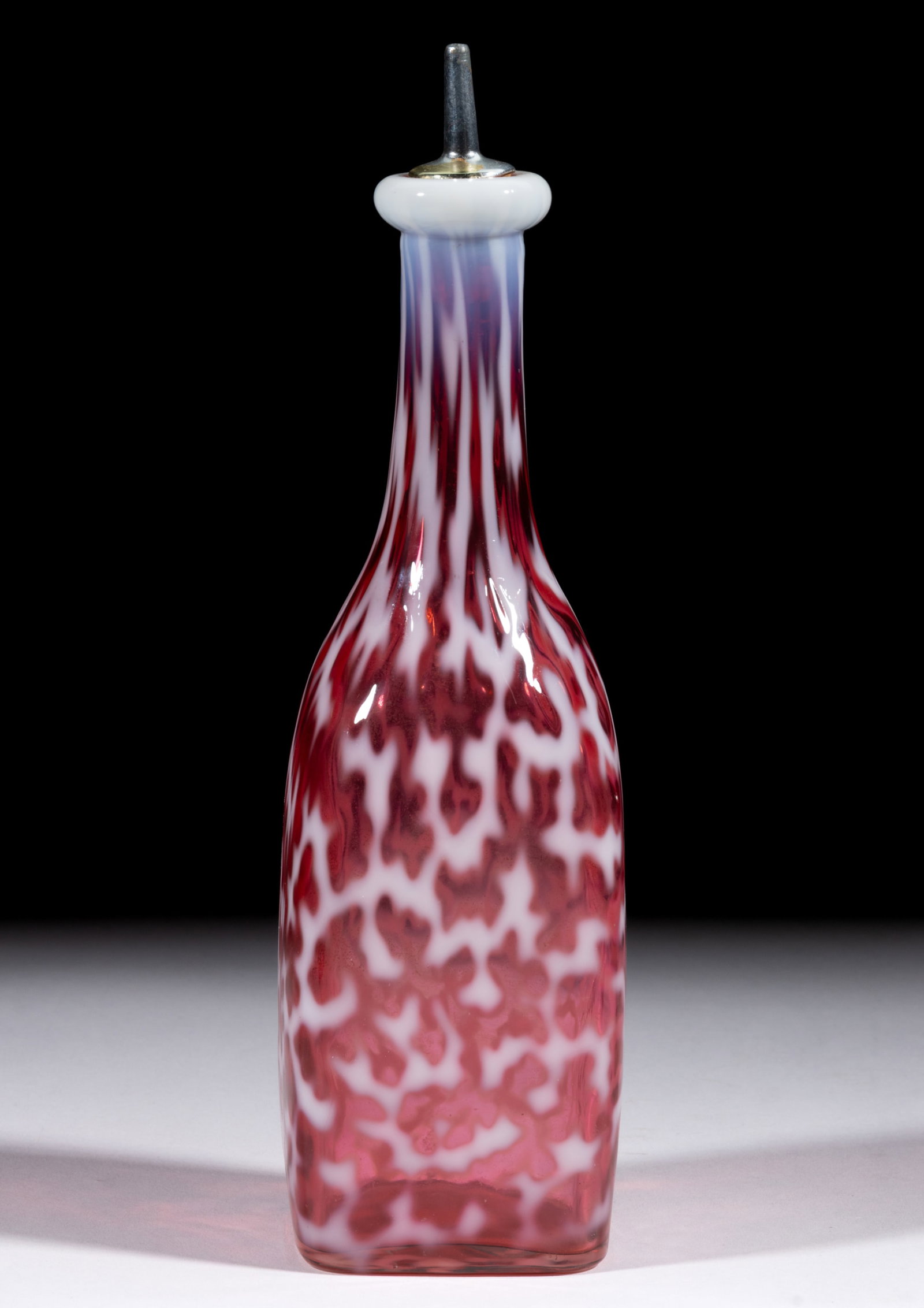 CORAL REEF BITTERS / BARBER'S BOTTLE: CORAL REEF BITTERS / BARBER'S BOTTLE, cranberry opalescent, square bottle form with metal and cork spout and polished pontil mark. Hobbs, Brockunier & Co. Late 19th/early 20th century. 9 1/2&q