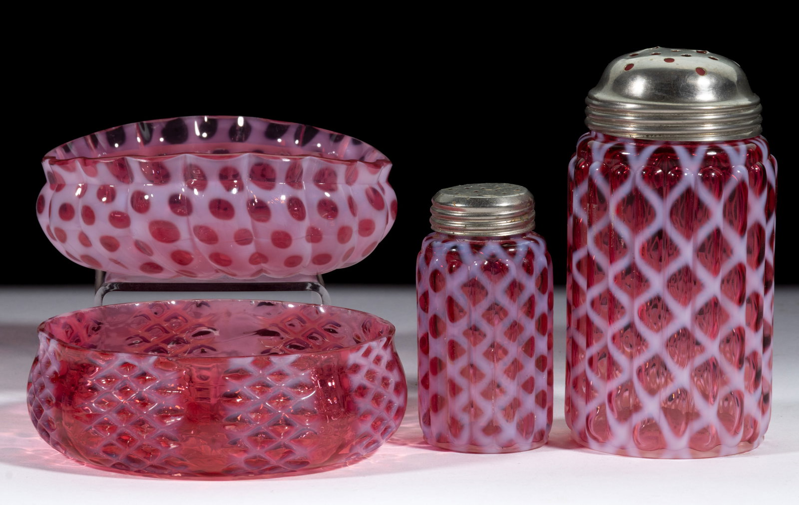 ASSORTED OPALESCENT GLASS TABLE ARTICLES, LOT OF FOUR: ASSORTED OPALESCENT GLASS TABLE ARTICLES, LOT OF FOUR, cranberry opalescent, comprising No. 326 (OMN) / Windows berry bowl, Criss-Cross berry bowl, Ribbed Opal Lattice sugar shaker, and salt/pepper sh