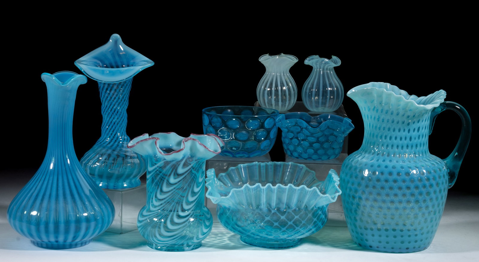 ASSORTED BLUE OPALESCENT GLASS ARTICLES, LOT OF NINE: ASSORTED BLUE OPALESCENT GLASS ARTICLES, LOT OF NINE, blue opalescent, including Northwood twist celery vase with pink rim, Fenton "Jack in the Pulpit" spiral optic vase, honeycomb pitcher w