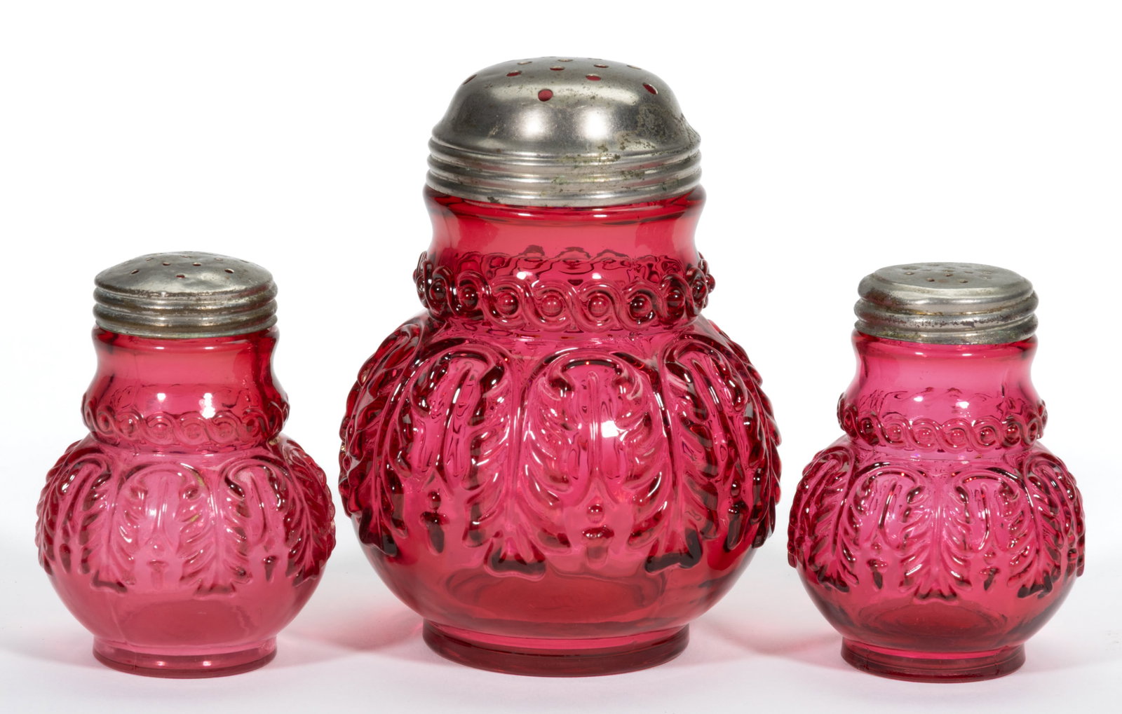 NORTHWOOD NO. 263 / LEAF UMBRELLA CONDIMENT ARTICLES, LOT OF THREE: NORTHWOOD NO. 263 / LEAF UMBRELLA CONDIMENT ARTICLES, LOT OF THREE, Ruby, comprising a sugar shaker, and salt and pepper shakers, each having a period lid. H. Northwood Glass Co. Pattern introduced in