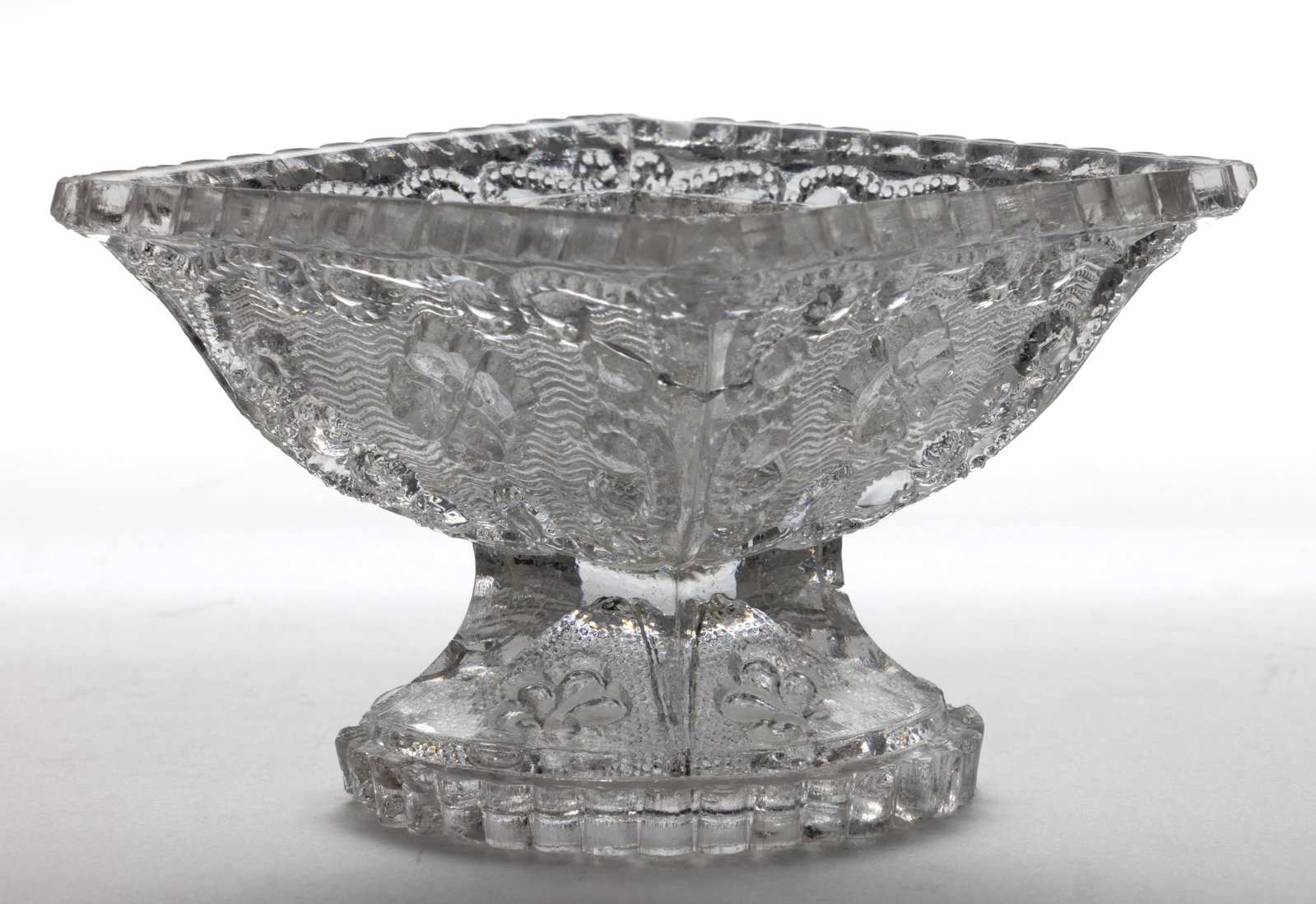 DD-2 DIAMOND PEDESTAL PRESSED OPEN SALT: DD-2 DIAMOND PEDESTAL PRESSED OPEN SALT, colorless, even-scallop rim over four panels each containing a four-petal flower on a finely stippled wavy ground framed by beaded scrolls, raised on a pedesta