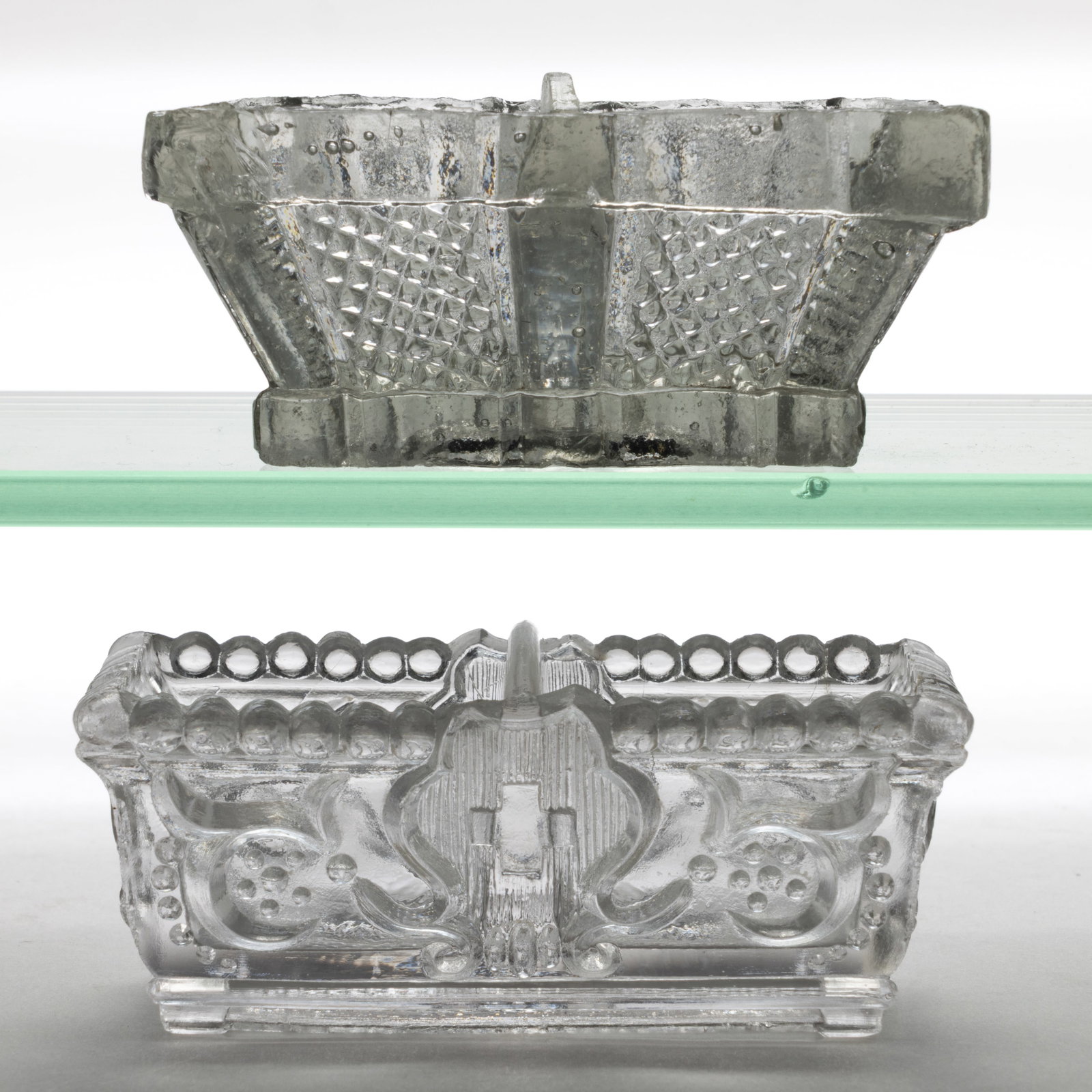 ASSORTED DI DIVIDED PRESSED OPEN SALTS, LOT OF TWO: ASSORTED DI DIVIDED PRESSED OPEN SALTS, LOT OF TWO, colorless, comprising a DI-6 Variant with no ornament on the panels and with a plain base, and an unlisted example having a large-bead rim, a centra