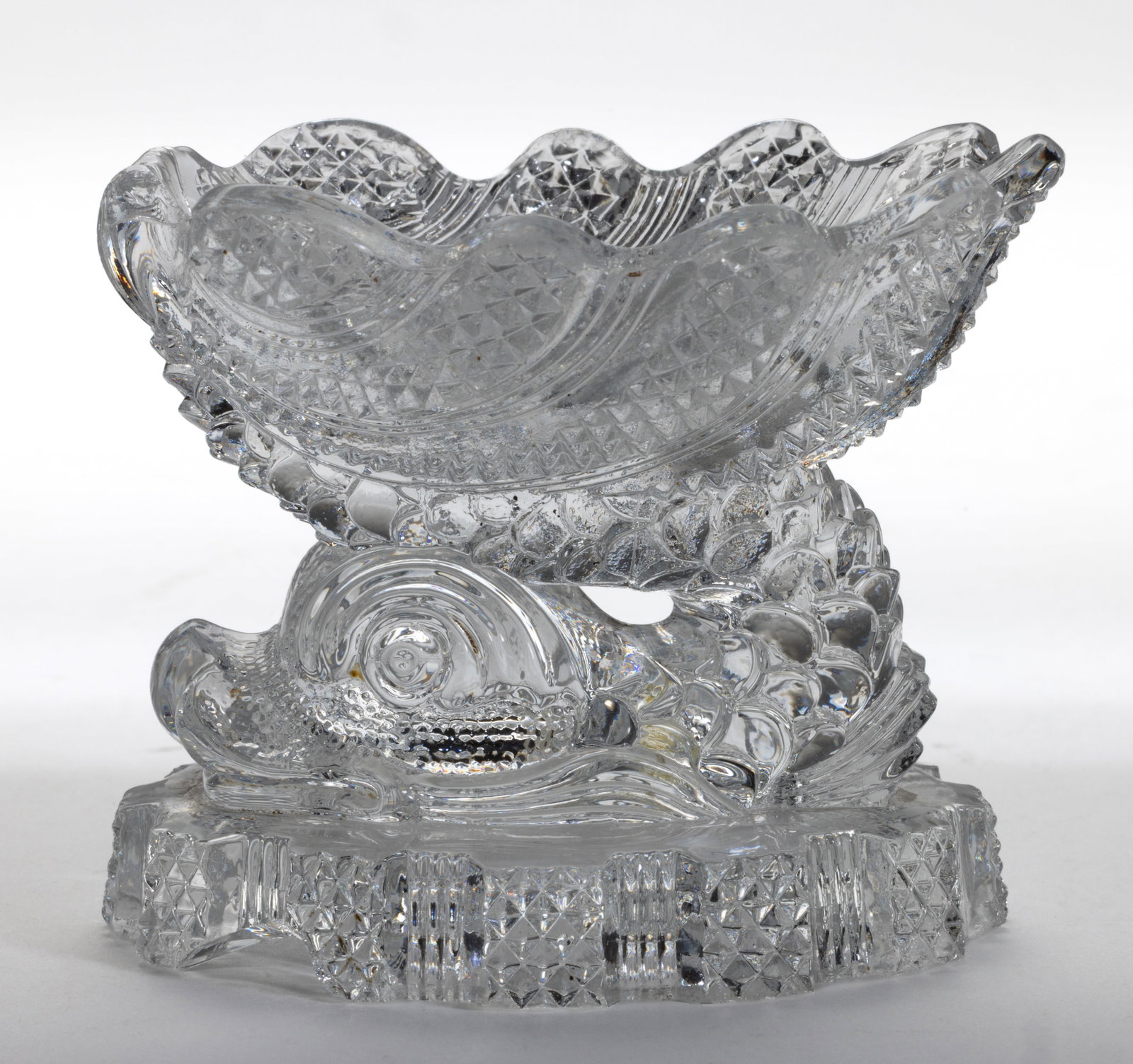 DN-1 DOLPHIN PRESSED OPEN SALT: DN-1 DOLPHIN PRESSED OPEN SALT, colorless, shell-form bowl raised on a dolphin standard and block-and-recess base. Extremely rare. France. 1830-1850. 2 1/2" H, 2 3/8" x 3" rim.