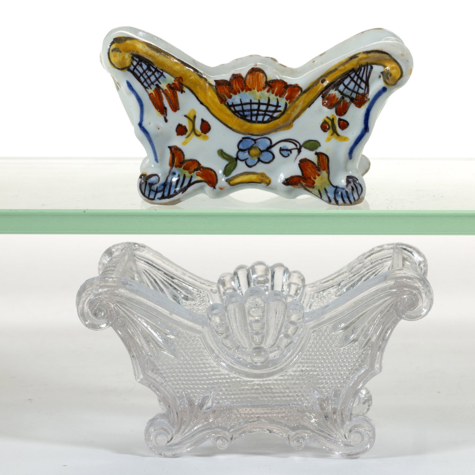 PN-2 CERAMIC AND SL-14 SHELL AND HAIRPIN PRESSED OPEN SALTS, LOT OF TWO: PN-2 CERAMIC AND SL-14 SHELL AND HAIRPIN PRESSED OPEN SALTS, LOT OF TWO, comprising a colorless glass example and an unmarked French Henriot Quimper ceramic example with plain base, each raised o