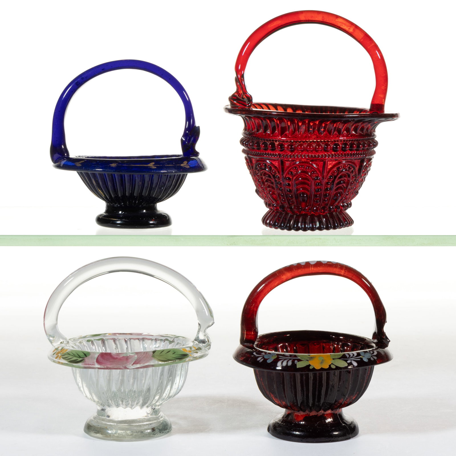 BLOWN / PRESSURE-MOLDED GLASS BASKET OPEN SALTS, LOT OF THREE: BLOWN / PRESSURE-MOLDED GLASS BASKET OPEN SALTS, LOT OF THREE, various colors, each with gilt or polychrome-enamel decoration to rim, applied handle, and ribbed body on circular foot. Together