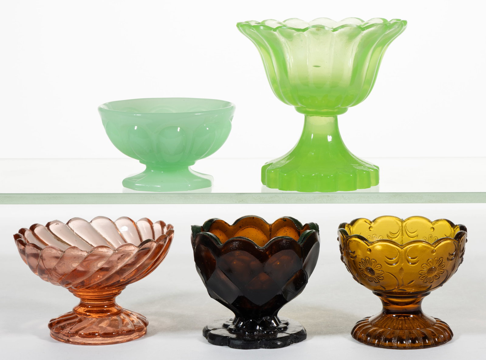 ASSORTED EARLY PRESSED GLASS PEDESTAL OPEN SALTS, LOT OF FIVE: ASSORTED EARLY PRESSED GLASS PEDESTAL OPEN SALTS, LOT OF FIVE, including a Jadeite (reacts under black light) Loop bowl on decagon foot, an amber Honeycomb bowl on nine scalloped foot, 