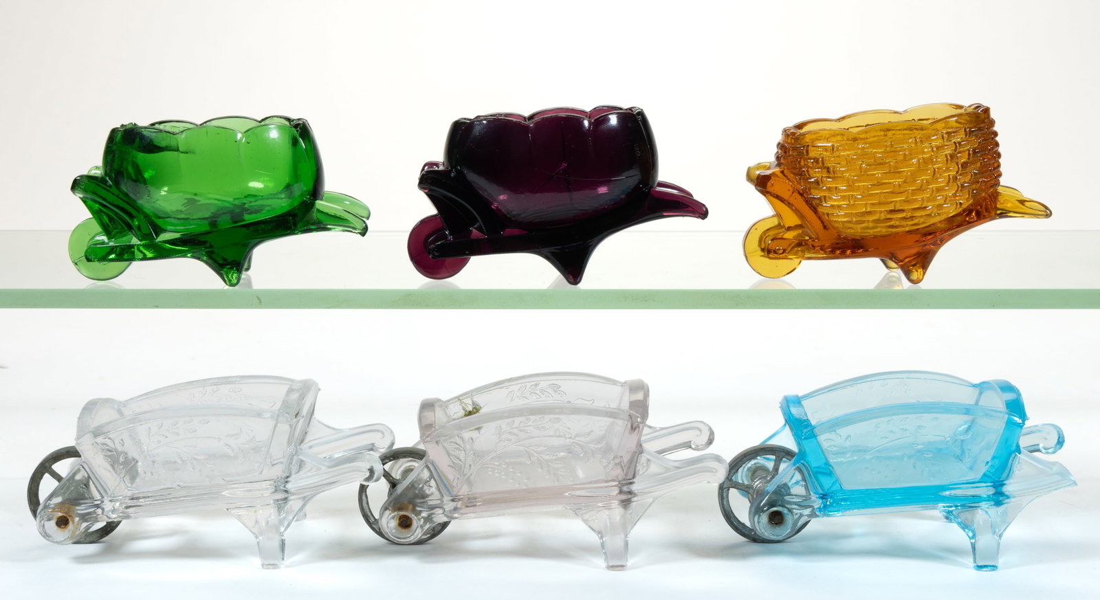 ASSORTED PRESSED FIGURAL WHEELBARROW GLASS OPEN SALTS, LOT OF SIX: ASSORTED PRESSED FIGURAL WHEELBARROW GLASS OPEN SALTS, LOT OF SIX, various colors, including an amber Greentown basketweave and three Good Luck / Horseshoe with original white-metal axle and wheel. Va