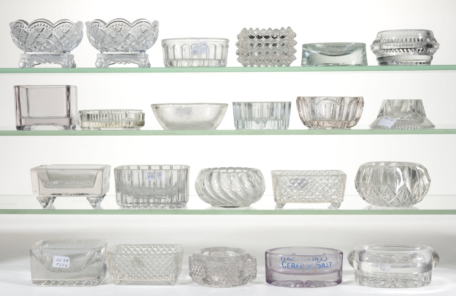 ASSORTED PRESSED GLASS OPEN SALTS, LOT OF 22: ASSORTED PRESSED GLASS OPEN SALTS, LOT OF 22, colorless, including a square hobnail, an amethyst tint with Cerebos Salt enamel advertisement, and two reproduction Fostoria examples. Various maker