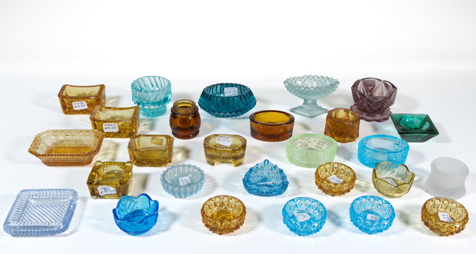 ASSORTED PRESSED COLORED GLASS OPEN SALTS, LOT OF 27: ASSORTED PRESSED COLORED OPEN SALTS, LOT OF 27, amber, amethyst, blue, green, and Vaseline (reacts under black light), comprising two Leaf and Rib, two Two Flower, a Triangle, an Octagon, an