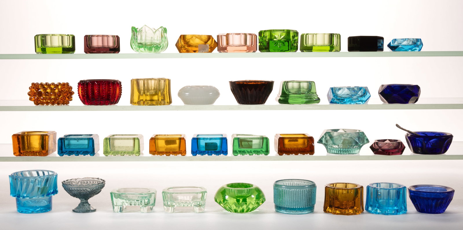ASSORTED PRESSED COLORED GLASS OPEN SALTS, LOT OF 36: ASSORTED PRESSED COLORED GLASS OPEN SALTS, LOT OF 36, various colors including apple green (reacts under black light), including a Fostoria Flemish, a Hobnail, and two Octagon. Various makers. Fo