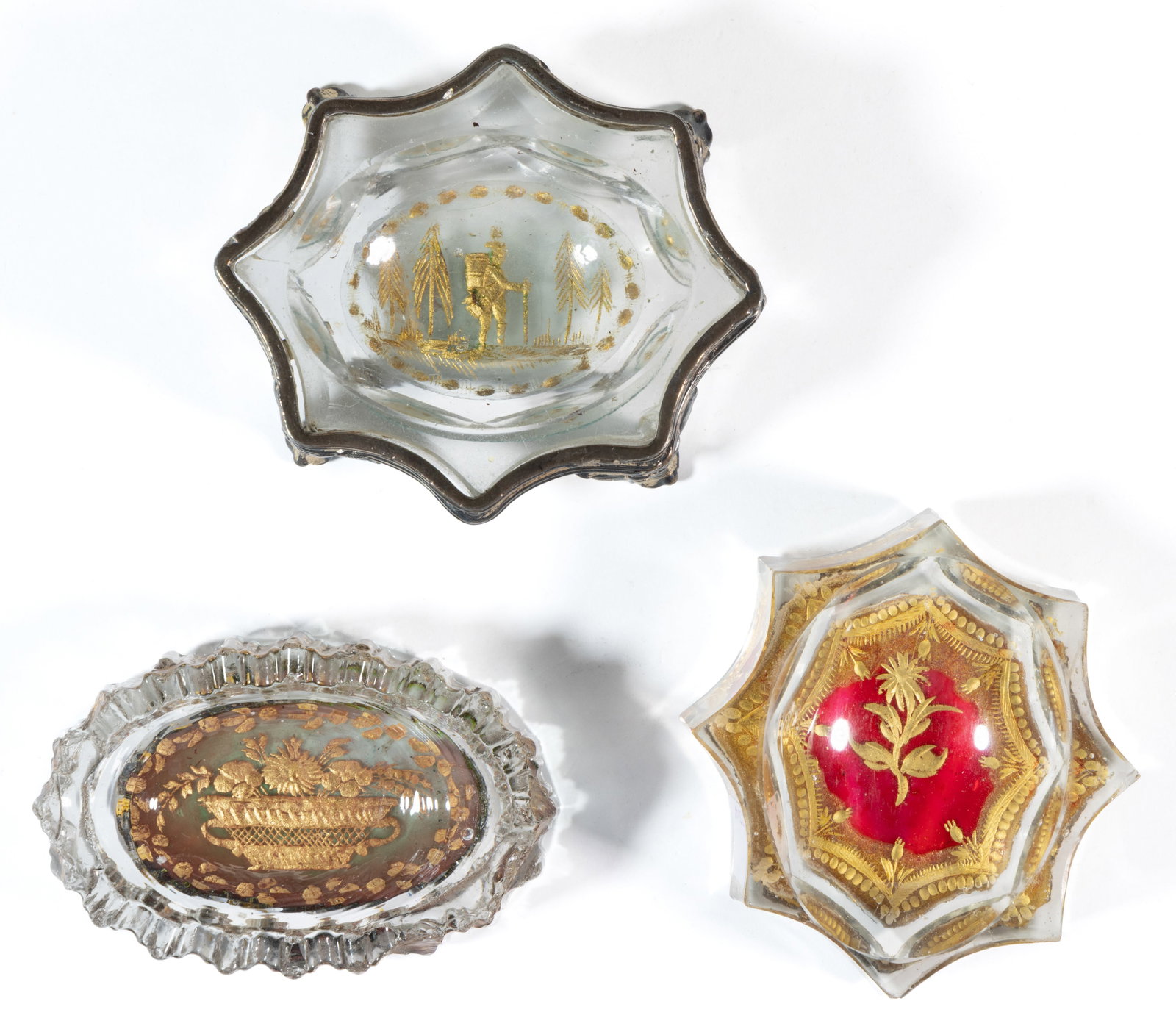 DOPPLEWANDGLAS / DOUBLE GLASS OPEN SALTS, LOT OF THREE: DOPPLEWANDGLAS / DOUBLE GLASS OPEN SALTS, LOT OF THREE, colorless, each with gilt decoration, two with applied stained cranberry base, comprising an example depicting a scenic scene fitted in met