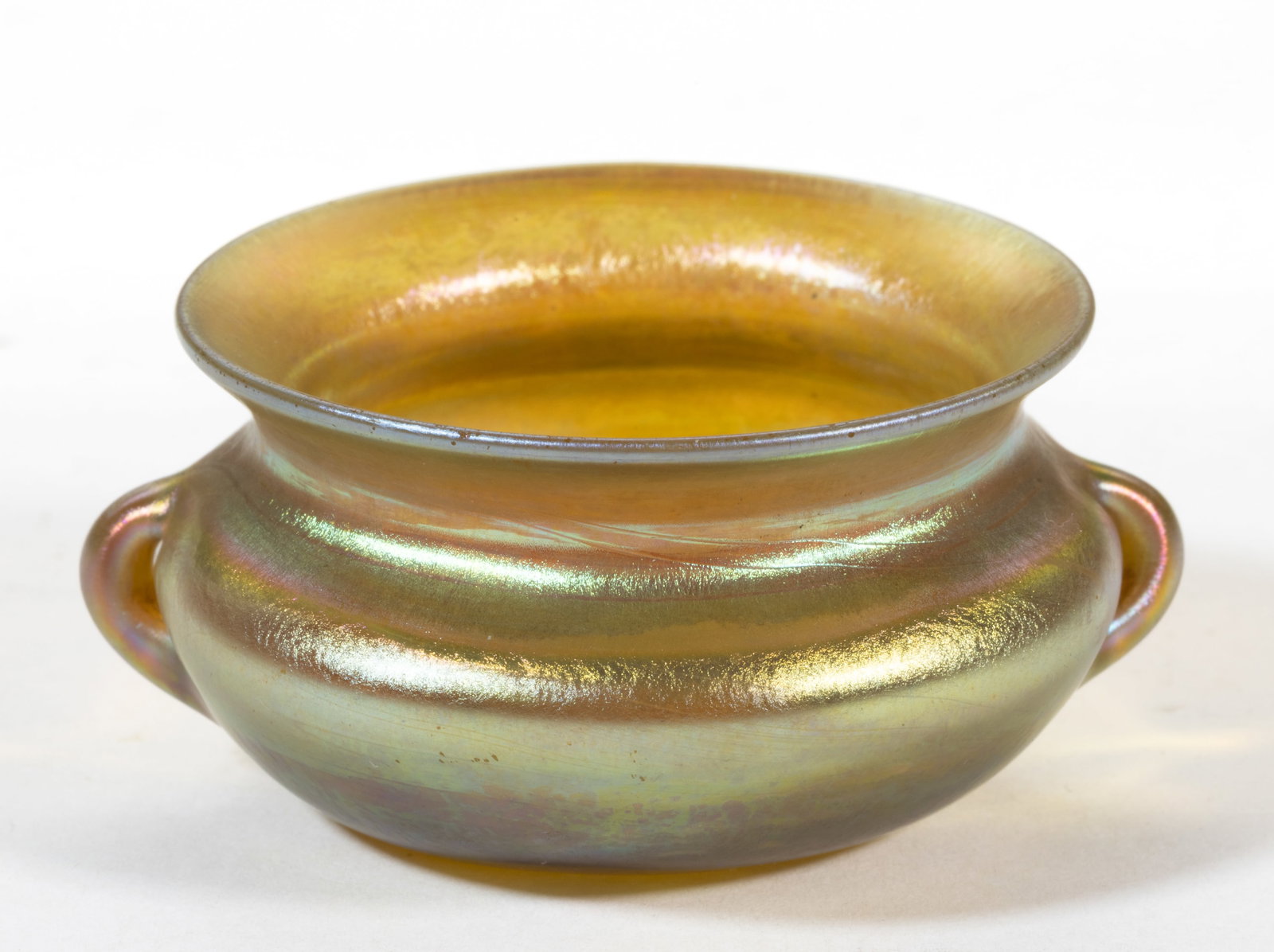 TIFFANY STUDIOS DOUBLE-HANDLED IRIDESCENT ART GLASS OPEN SALT: TIFFANY STUDIOS DOUBLE-HANDLED IRIDESCENT ART GLASS OPEN SALT, golden iridescent, cauldron form with two small formed handles to the side, signed to the underside, "L.C.T. 6328", polished po