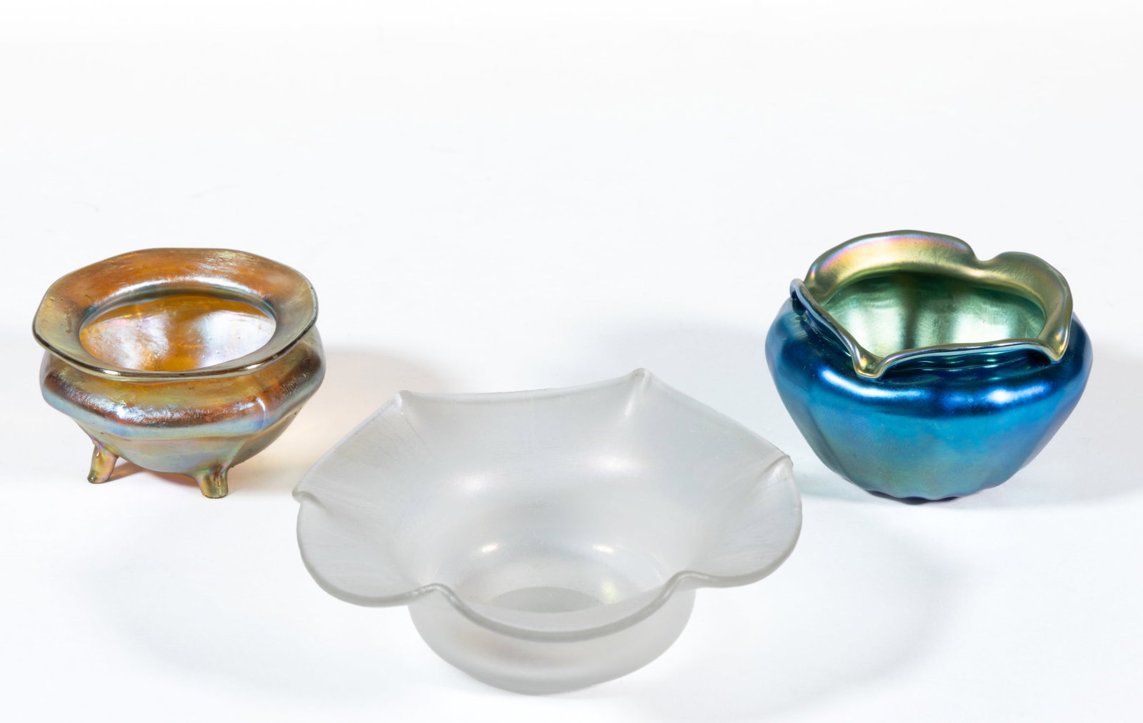 IRIDESCENT ART GLASS OPEN SALTS, LOT OF THREE: IRIDESCENT ART GLASS OPEN SALTS, LOT OF THREE, comprising a Steuben Verre De Soie shape 138, flat form with gauffered rim, a gold iridescent Tiffany Favrile with factory-polished to lev