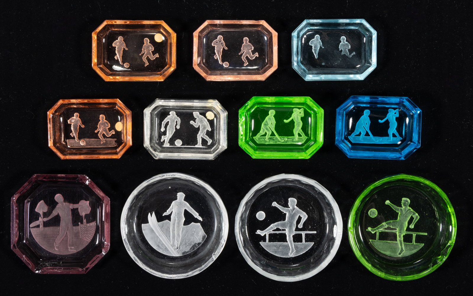 INTAGLIO GLASS OPEN SALTS, LOT OF 11: INTAGLIO GLASS OPEN SALTS, LOT OF 11, various colors including one apple green (reacts under black light), each depicting a sporting scene, including one featuring a tennis player, a skier, and&n
