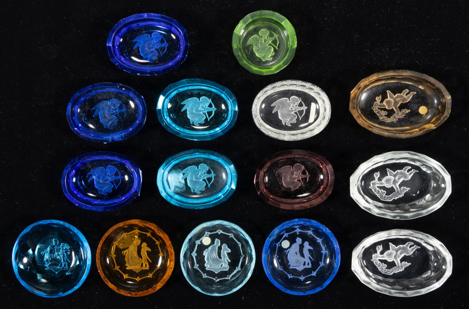 INTAGLIO GLASS OPEN SALTS, LOT OF 15: INTAGLIO GLASS OPEN SALTS, LOT OF 15, various colors, each featuring a putto, including three with festoon, and eight with bow and arrow, each having a factory-polished rim and edge. Cz