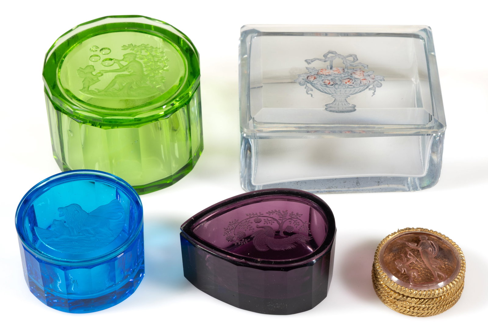 INTAGLIO GLASS BOXES, LOT OF FIVE: INTAGLIO GLASS BOXES, LOT OF FIVE, various colors, comprising two featuring a Classical scene, one a peacock and fruit tree, one a lion and lioness, and one a floral arrangement. Czechoslovakia. Circa