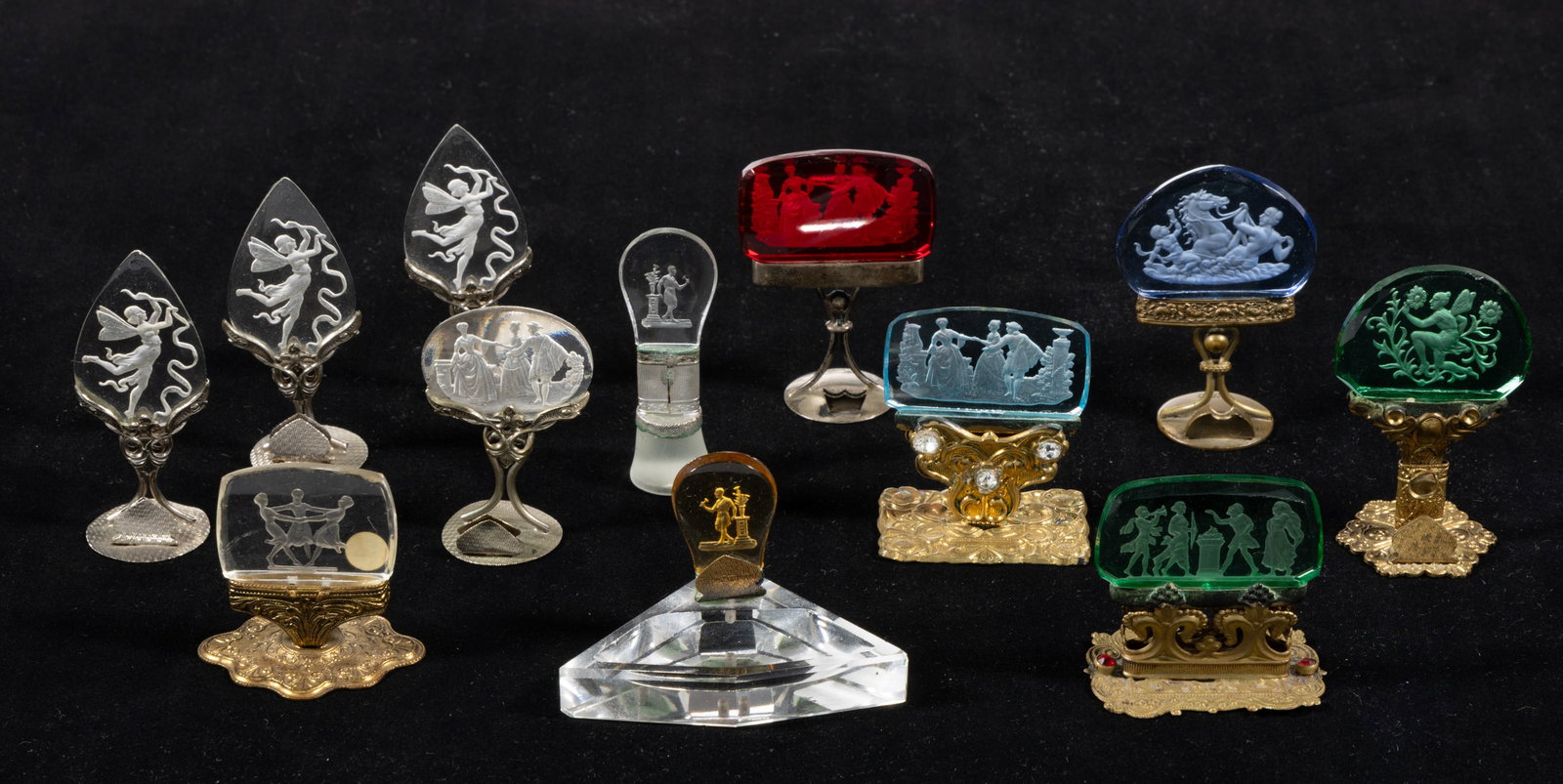 CZECHOSLOVAKIAN INTAGLIO GLASS PLACE CARD HOLDERS, LOT OF 12: CZECHOSLOVAKIAN INTAGLIO GLASS PLACE CARD HOLDERS, LOT OF 12, various colors, including three with Colonial figures, one with dancing Art Deco figures, and remainder with Classical scenes, m