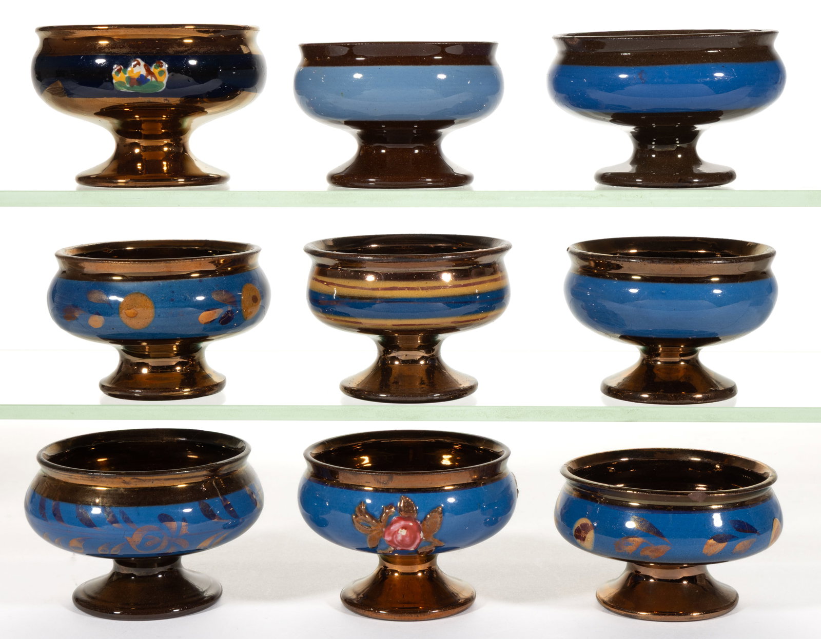 BRITISH COPPER LUSTRE AND OTHER SIMILAR CERAMIC OPEN SALTS, LOT OF NINE: BRITISH COPPER LUSTRE AND OTHER SIMILAR CERAMIC OPEN SALTS, LOT OF NINE, each of pedestal form with blue band decoration, including two examples having stylized floral design and two examples fea
