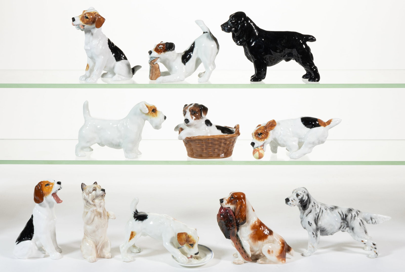 ENGLISH ROYAL DOULTON HAND-PAINTED PORCELAIN DOG FIGURES, LOT OF 11: ENGLISH ROYAL DOULTON HAND-PAINTED PORCELAIN DOG FIGURES, LOT OF 11, comprising one beagle pup nestled in a basket, one begging Cairn Terrier, one spaniel holding a pheasant in its mouth, one Sea