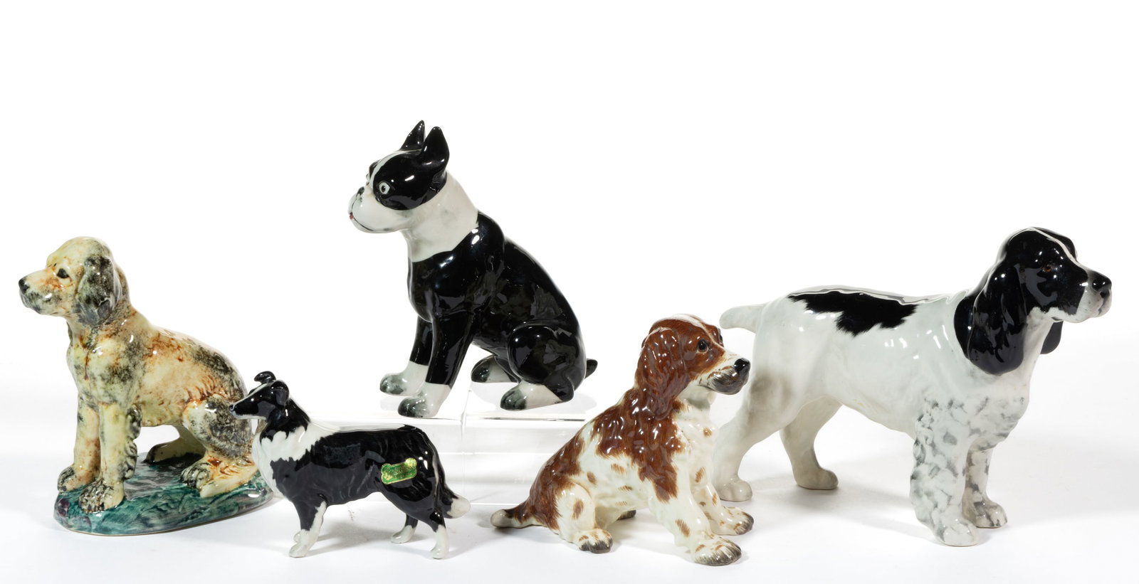 AMERICAN AND ENGLISH HAND-PAINTED PORCELAIN DOG FIGURES, LOT OF FIVE: AMERICAN AND ENGLISH HAND-PAINTED PORCELAIN DOG FIGURES, LOT OF FIVE, comprising a Stangl example featuring a sitting pup on an ovoid green base, a Gort example depicting a brown-spotted puppy with la