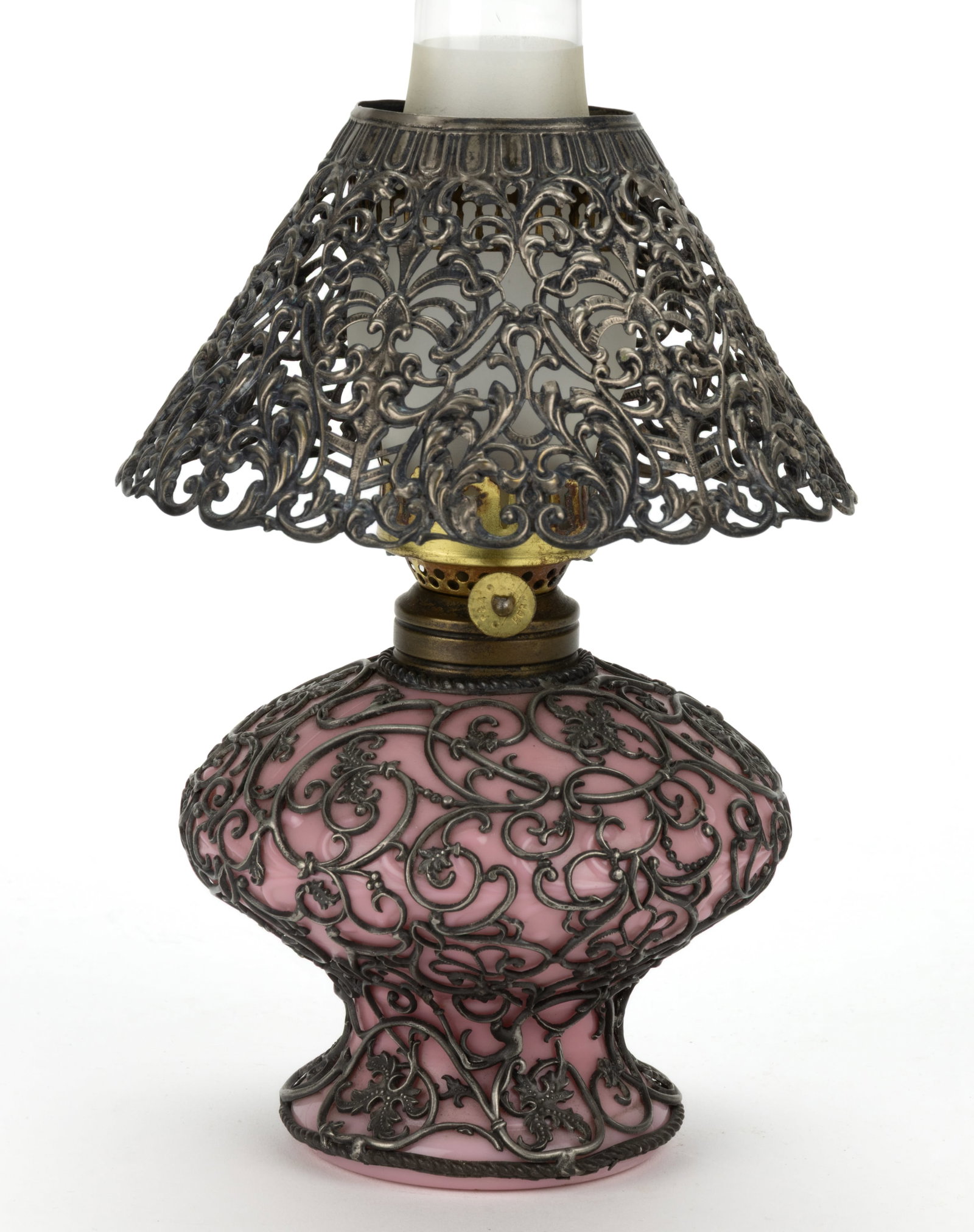 SCROLL BAND EMBOSSED WITH FILIGREE MINIATURE LAMP BASE: SCROLL BAND EMBOSSED WITH FILIGREE MINIATURE LAMP BASE, opaque pink globular-form font with short circular pedestal-form foot, encased in silver-toned filigree with ornate floral, oak-leaf and sc