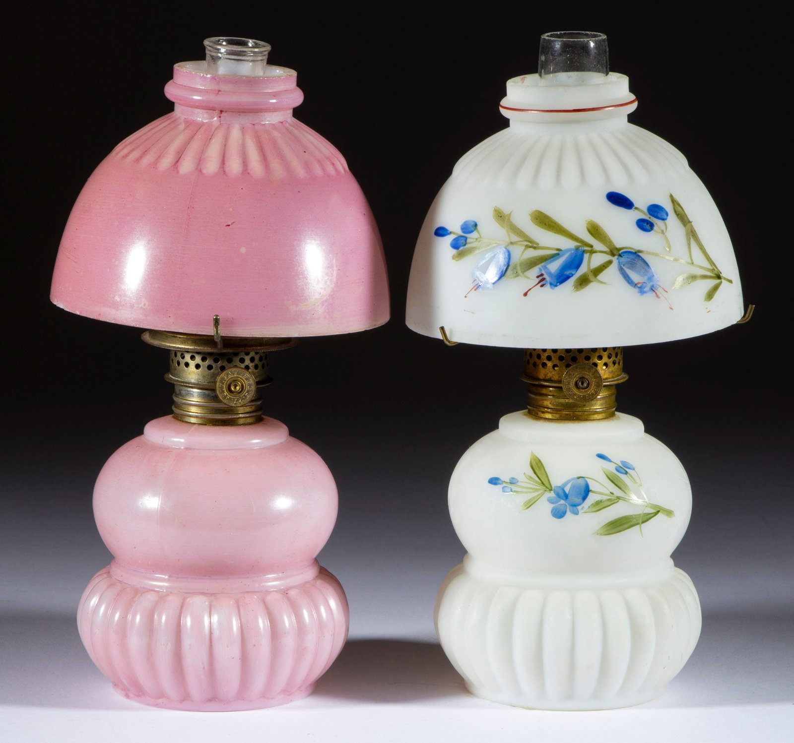 BABY MCKEE MINIATURE LAMPS, LOT OF TWO: BABY MCKEE MINIATURE LAMPS, LOT OF TWO, opaque white, comprising a satin example with blue and green enamel floral decoration; and an example with pink ground, each with a matching decorated and patte