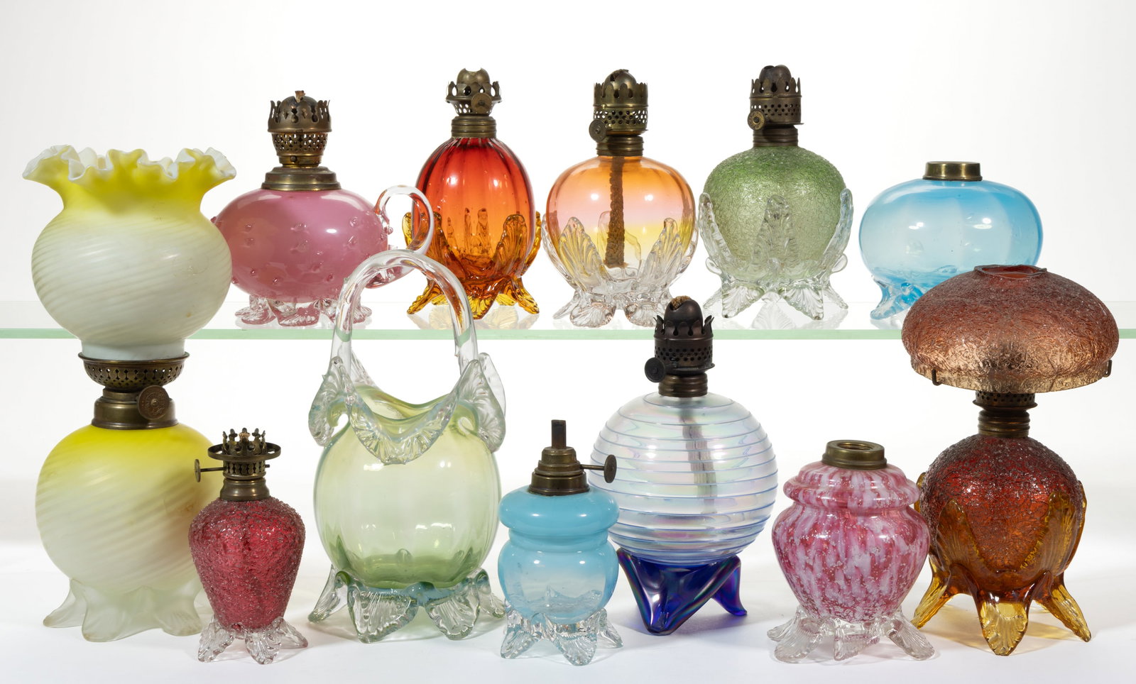 ASSORTED ART GLASS MINIATURE LAMP FONTS, LOT OF 11: ASSORTED ART GLASS MINIATURE LAMP FONTS, LOT OF 11, various colors, various forms of fonts and each having an applied base, patterns include a cased ruby/red with overshot Smith II, fig. XXII; a blue 