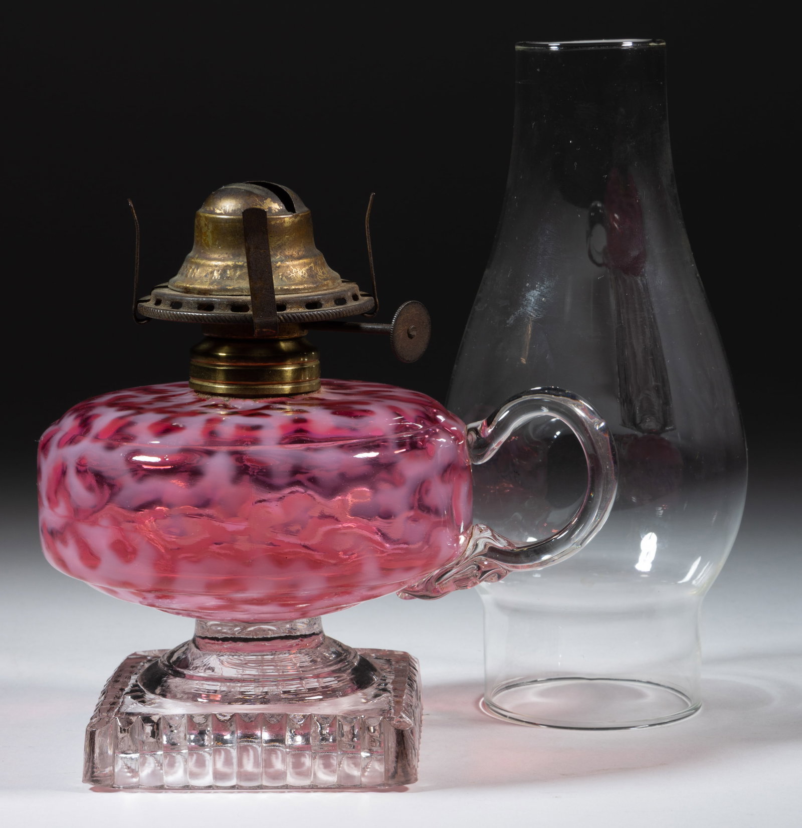 HOBBS CORAL REEF / SEAWEED KEROSENE FOOTED FINGER LAMP: HOBBS CORAL REEF / SEAWEED KEROSENE FOOTED FINGER LAMP, Ruby/cranberry opalescent font, colorless stem and ribbed foot, applied colorless handle with pressed fan design to the lower terminal