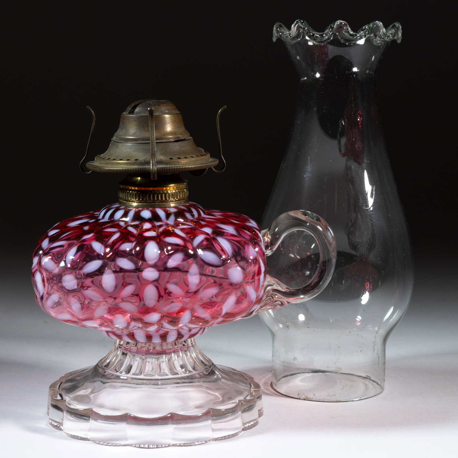HOBBS NO. 341 / SNOWFLAKE KEROSENE FOOTED FINGER LAMP: HOBBS NO. 341 / SNOWFLAKE KEROSENE FOOTED FINGER LAMP, Ruby/cranberry opalescent font, colorless base, applied colorless handle with pressed fan design to the lower terminal, No. 1 Miller Oval Ba