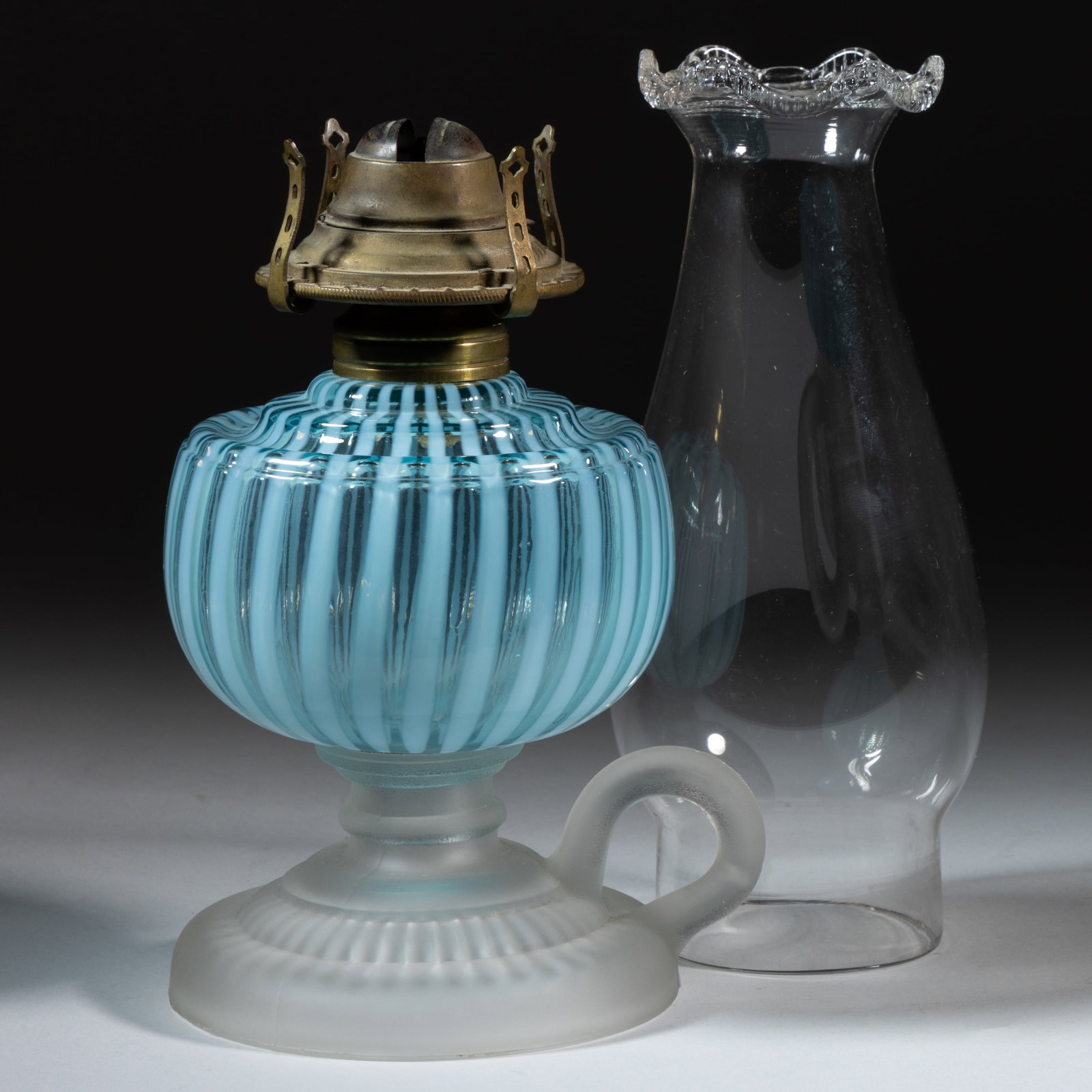 VENETIAN / VENICE KEROSENE FOOTED FINGER LAMP: VENETIAN / VENICE KEROSENE FOOTED FINGER LAMP, blue opalescent stripe font, drip-guard shoulder, colorless base with frosted finish and having a molded handle, No. 1 Taplin-Brown collar. Fit