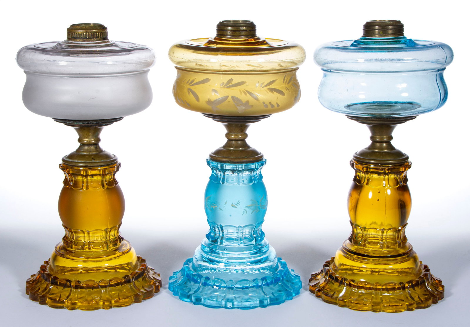 APOLLO KEROSENE COMPOSITE STAND LAMPS, LOT OF THREE: APOLLO KEROSENE COMPOSITE STAND LAMPS, LOT OF THREE, comprising one having a blue font and amber base, one with an amber font with enamel-decoration and a blue base, and one having a colorless font wi