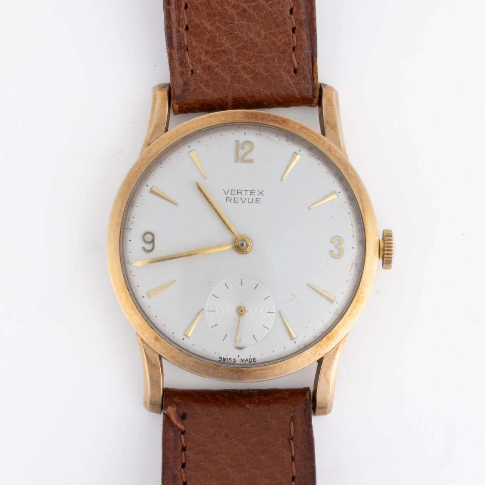 VINTAGE VERTEX REVUE WRIST WATCH: VINTAGE VERTEX REVUE WRIST WATCH,15-jewels, silver-colored dial with gold indices and Arabic numerals with sub-dial at 6 position, housed in a round yellow gold-colored case with brown leather strap. 